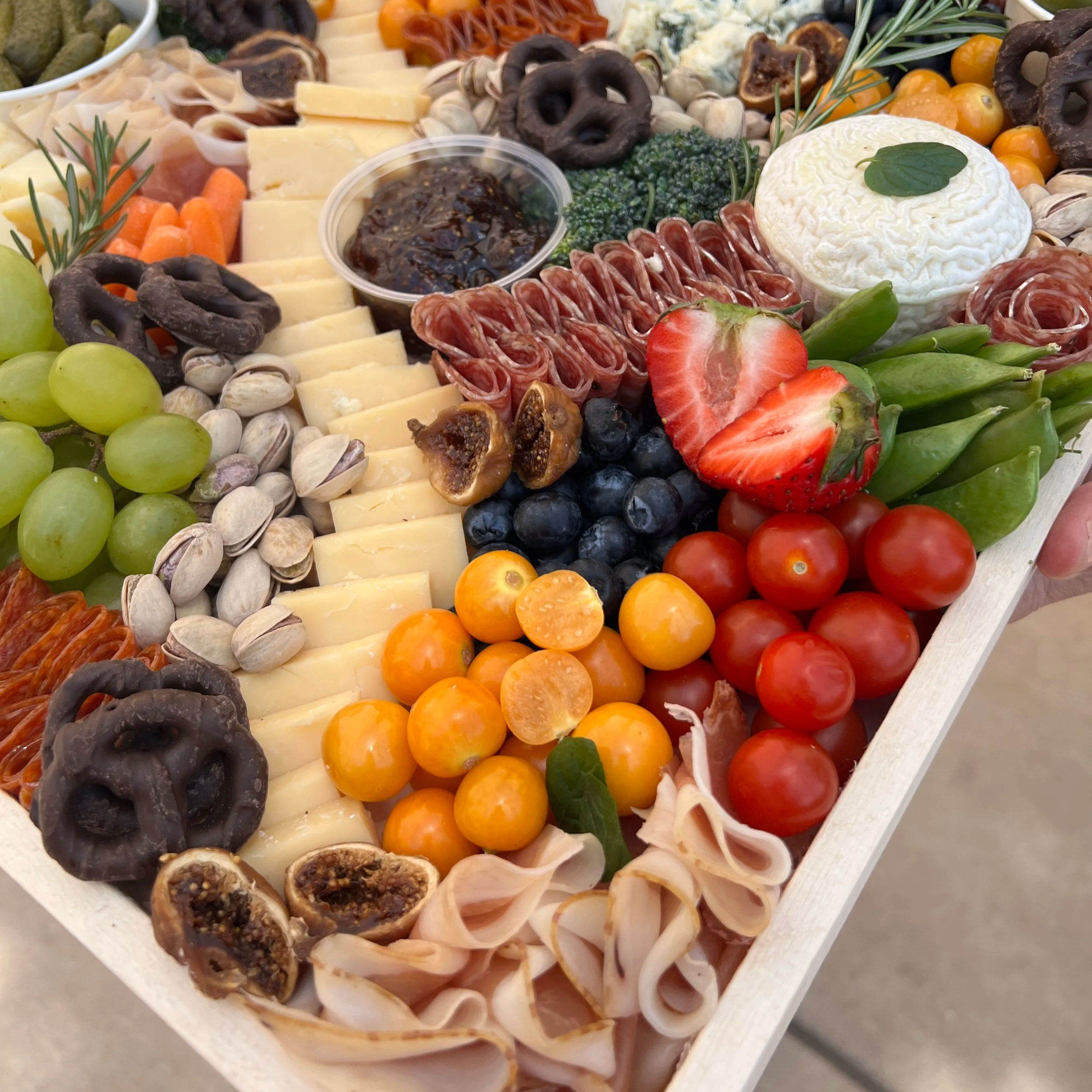 large grazing charcuterie board filled with cheese, nuts, meat, jam, fruit, and veggies