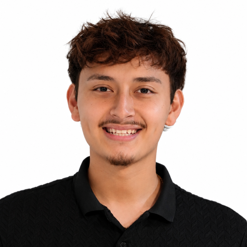 A young man with brown, curly hair and a light mustache and goatee, smiling and wearing a black collared shirt against a white background.