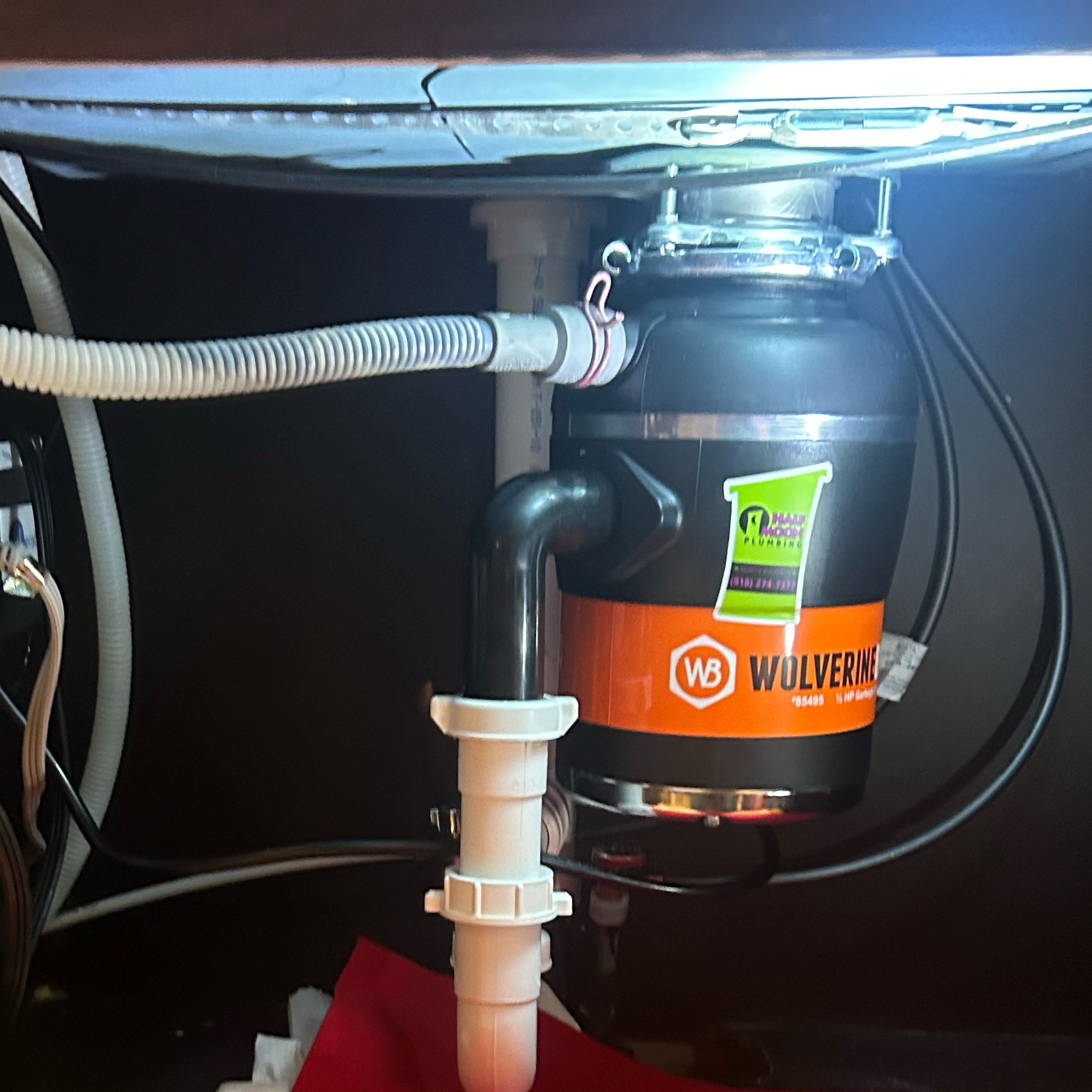 Kitchen sink garbage disposal unit installed under a sink, with visible pipes and plumbing connections.