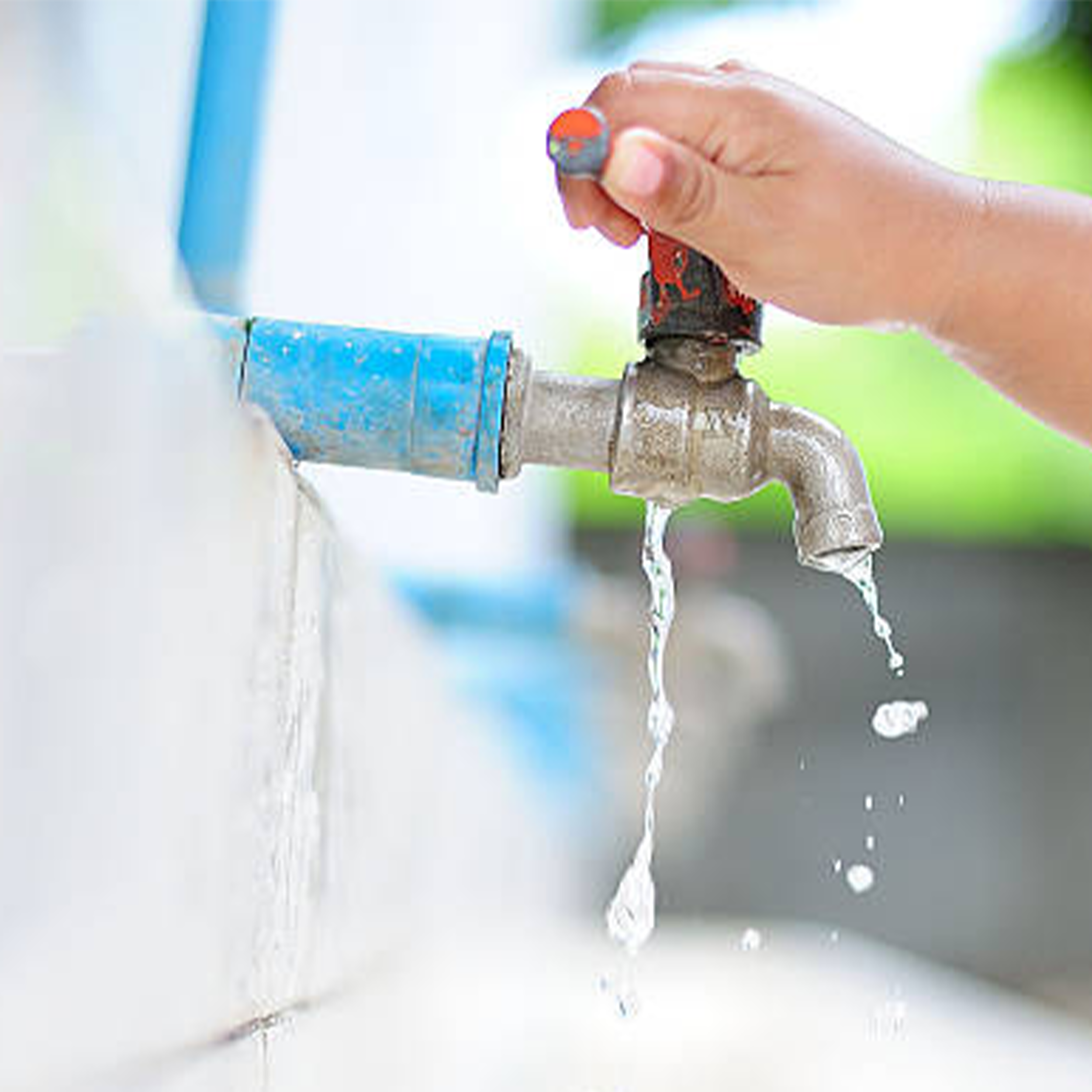 Close-up of a hand turning on a water faucet with water flowing out