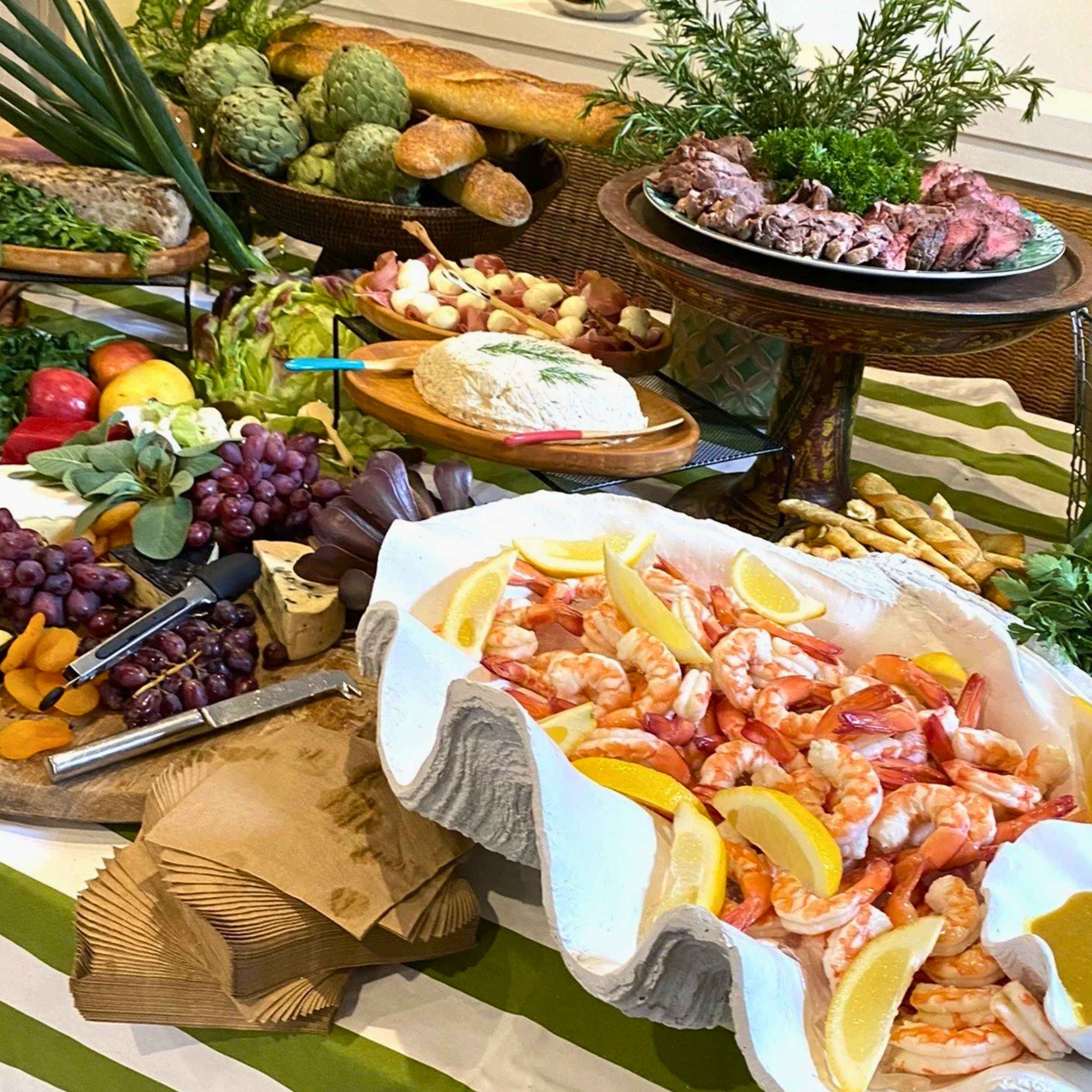Assorted seafood, vegetables, bread, and fruits on a buffet table with lemon slices and garnished with herbs.