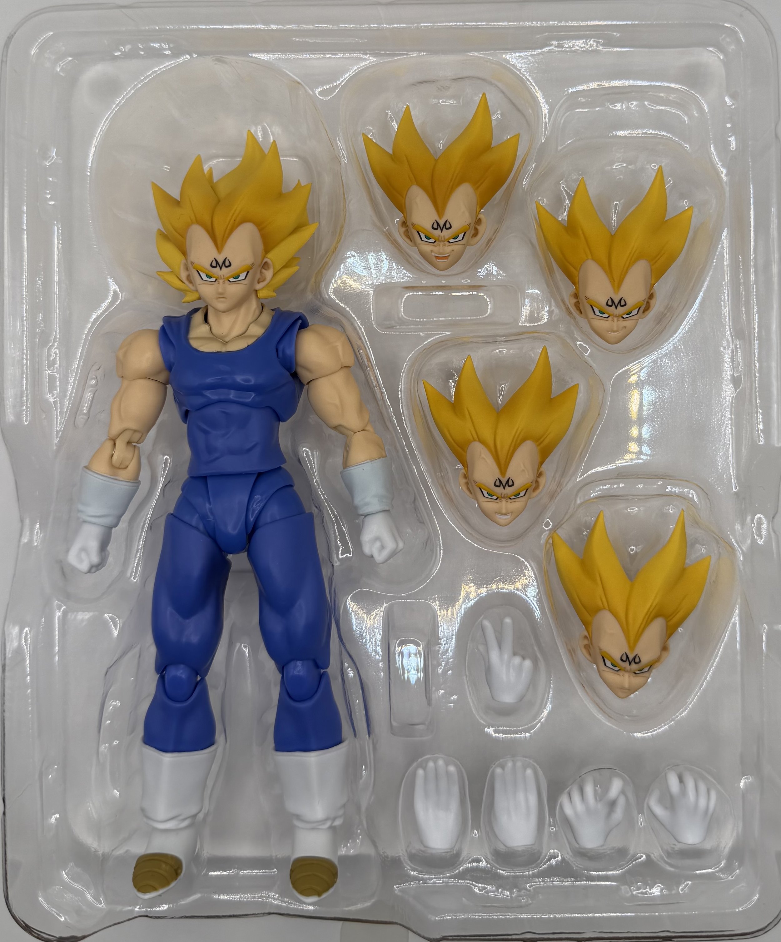 A Dragon Ball Z Super Saiyan Goku action figure with multiple interchangeable face and hand parts in a plastic tray.