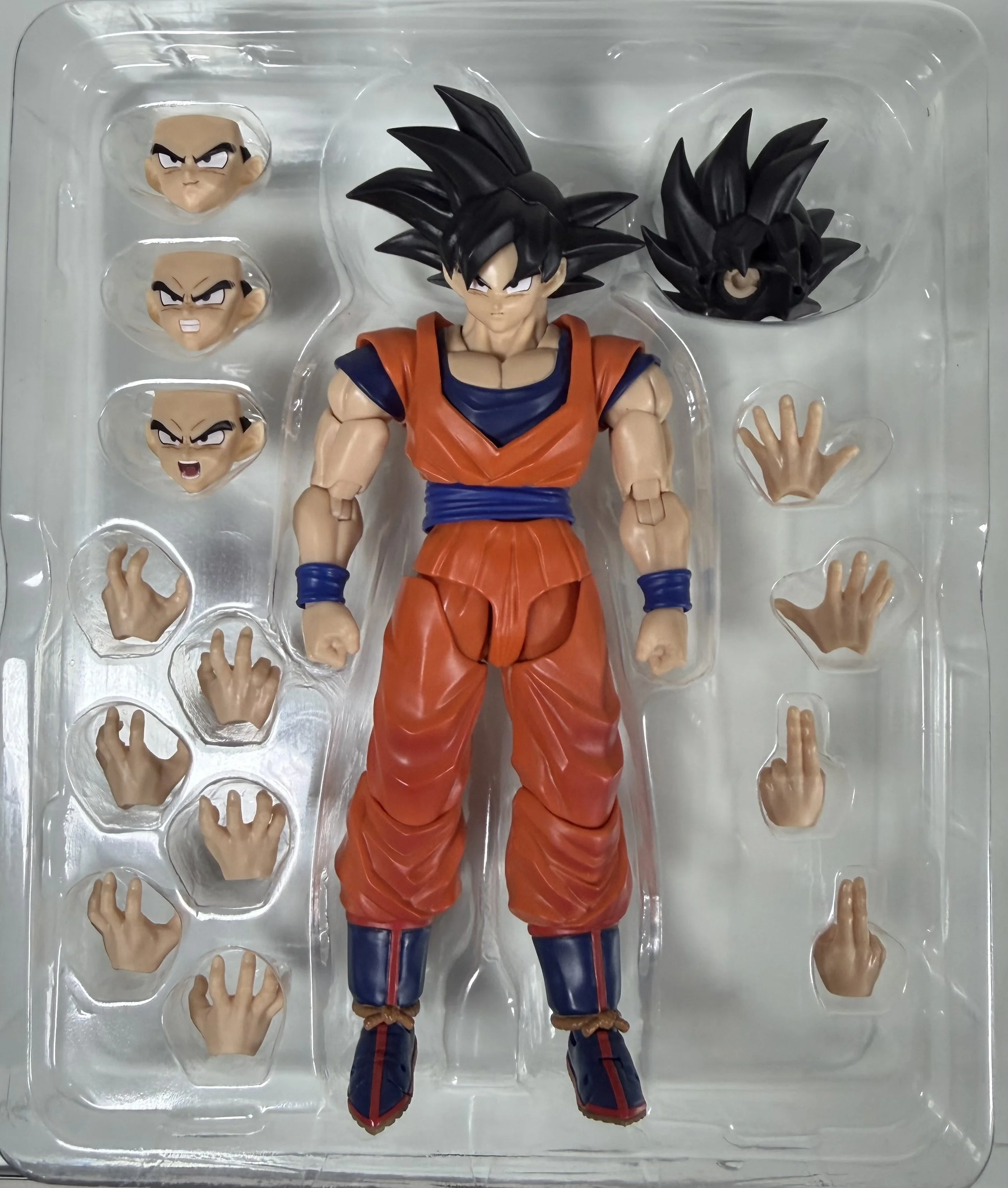 Action figure of Goku from Dragon Ball with interchangeable hands and faces in a plastic tray.