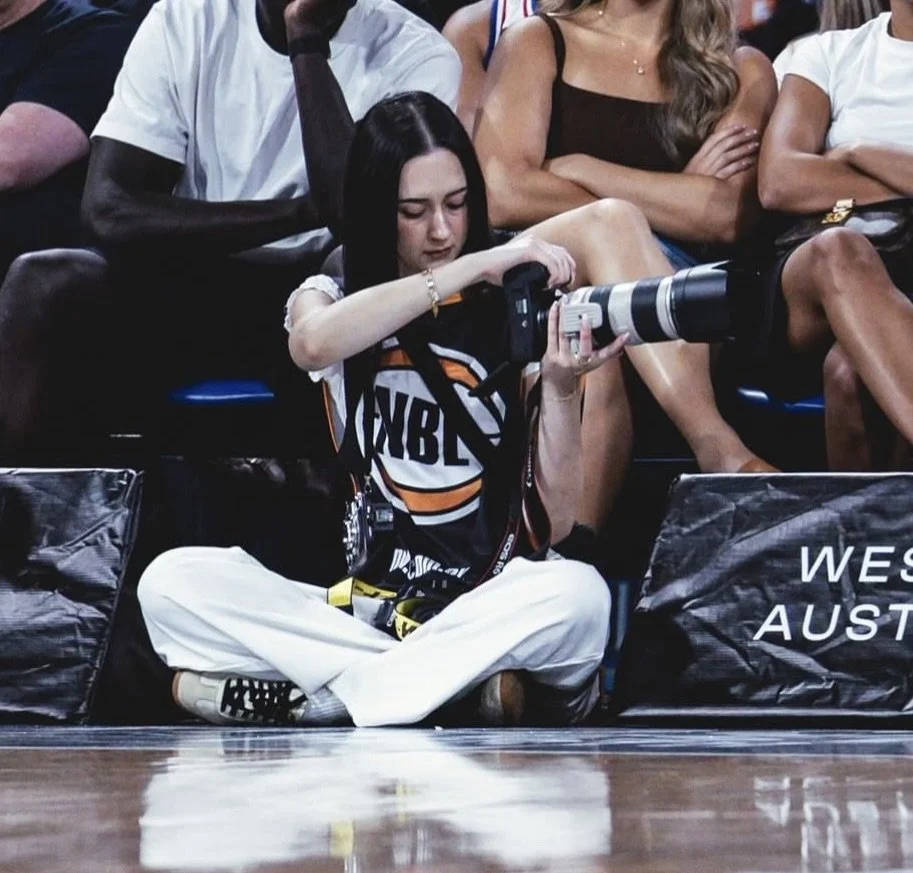 Tiarna Rose taking photos at an indoor basketball event