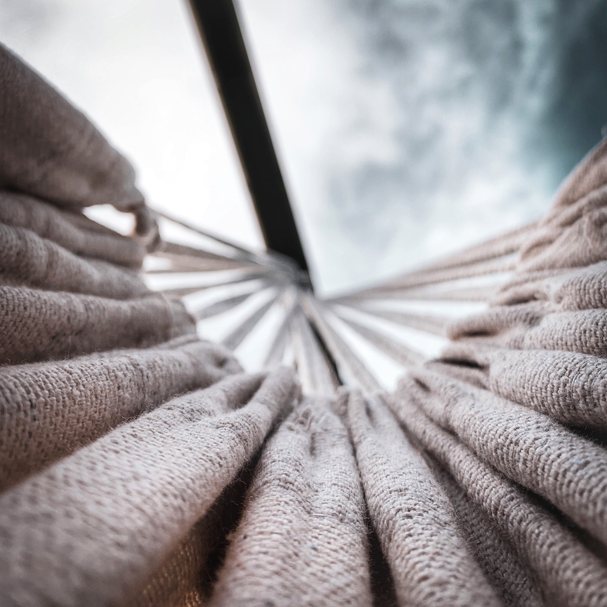 Texture de tissus enroulés, capturée en contre-plongée avec un ciel nuageux en arrière-plan, offrant une perspective abstraite des formes et des matériaux, photographié par Yoann Vareille, photographe abstrait à Brive-la-Gaillarde, Corrèze, Nouvelle-