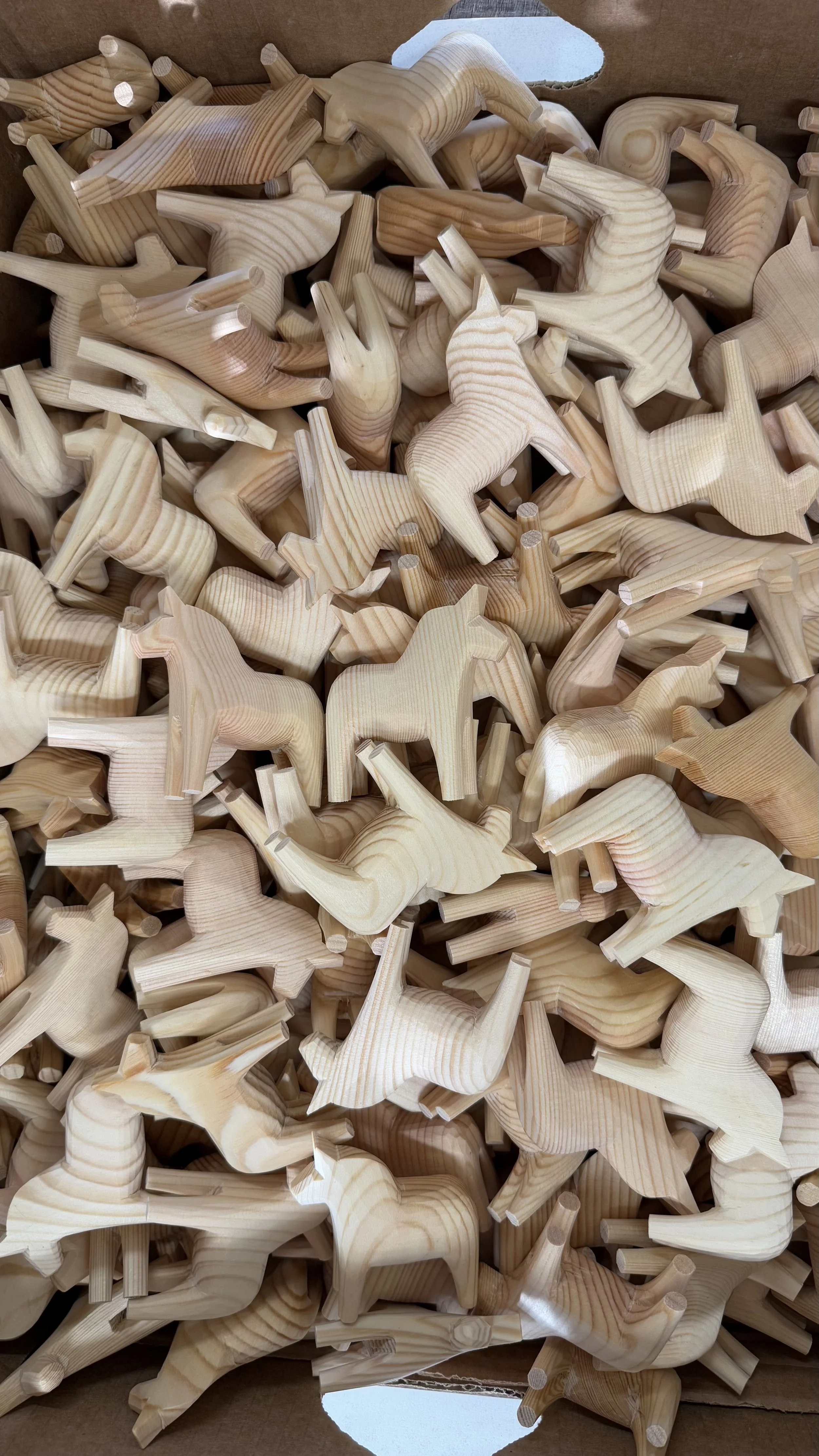 Viele unbemalte Dala-Pferde in einer Kiste