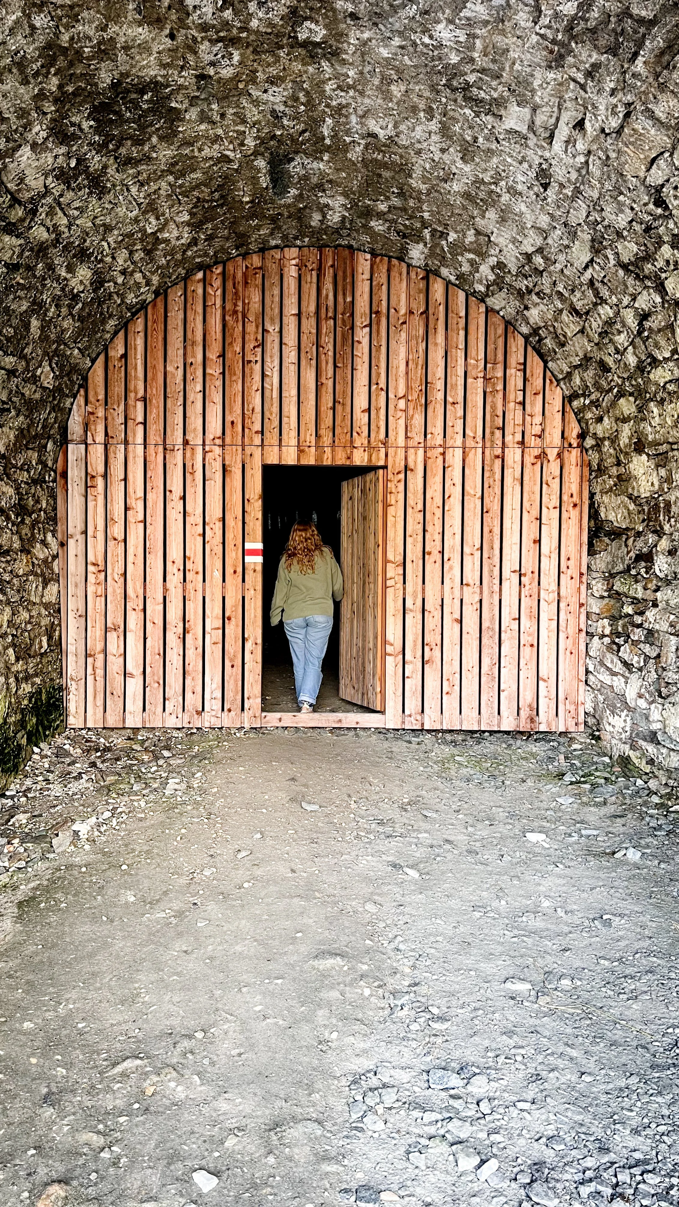 Frau erkundet Eingang in alten Tunnel, durch den ein Wanderweg führt.