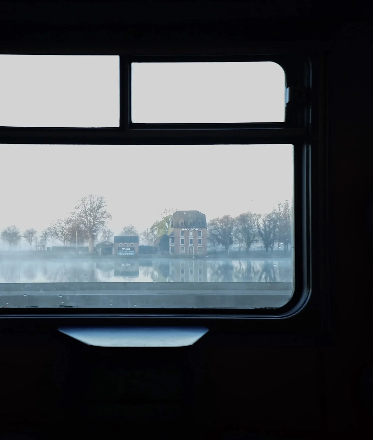 Aussicht aus einem Zug auf einen See, Häuser und Bäume