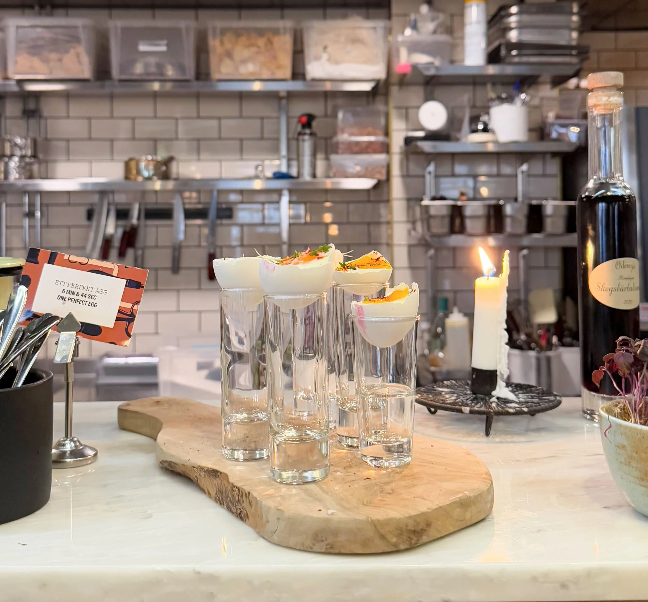 Halbe gekochte Eier in einem Schnapsglas auf einem Holzbrett. In der Industrialküche des Hotel Frantz in Stockholm.