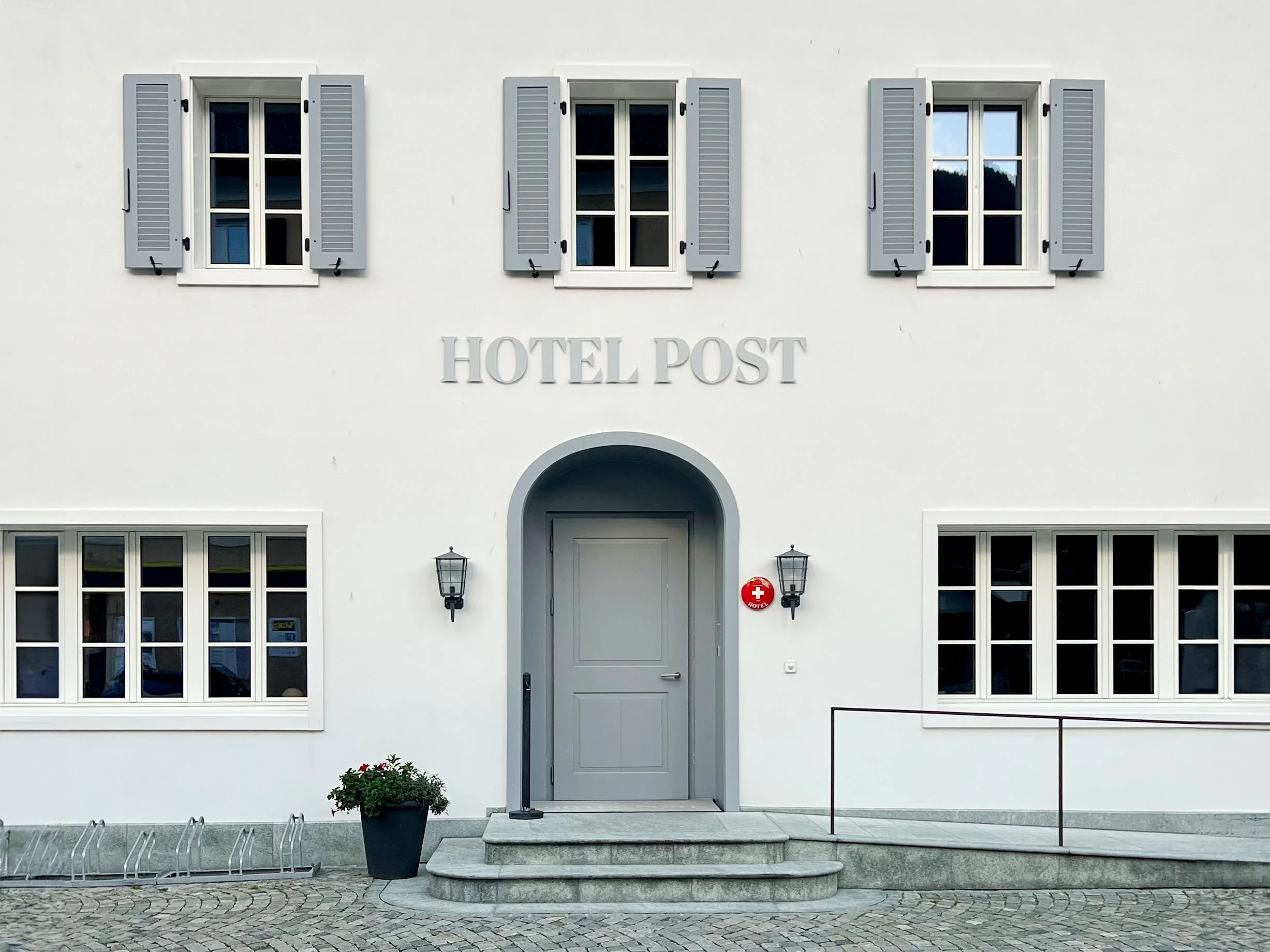 Weisse Hausfassade des Hotel Post in Andeer. Graue Fensterläden, historischer Bau.