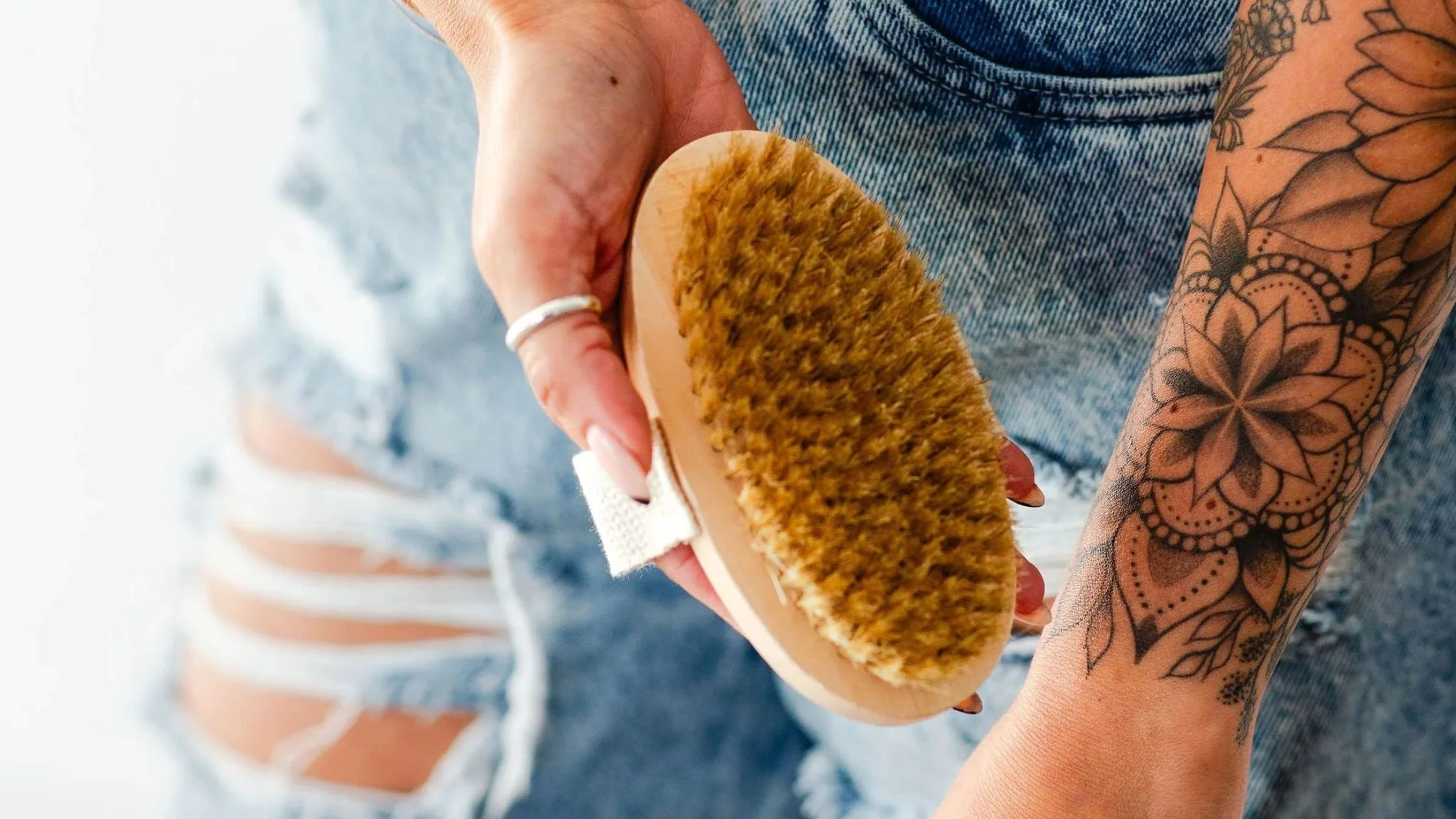 Person holding a wooden dry brush next to their arm