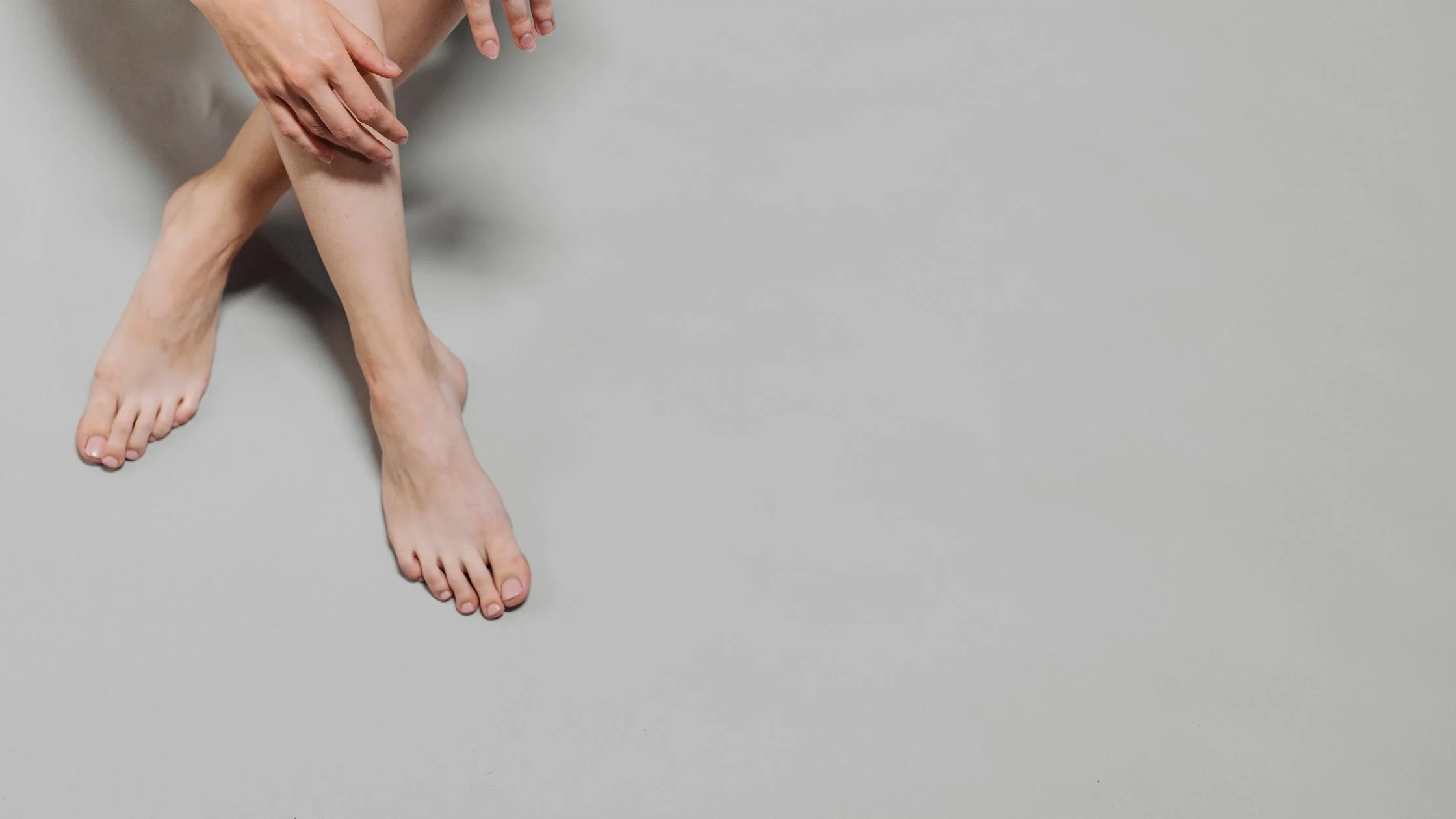 Person sitting with legs crossed and hands resting on their shin