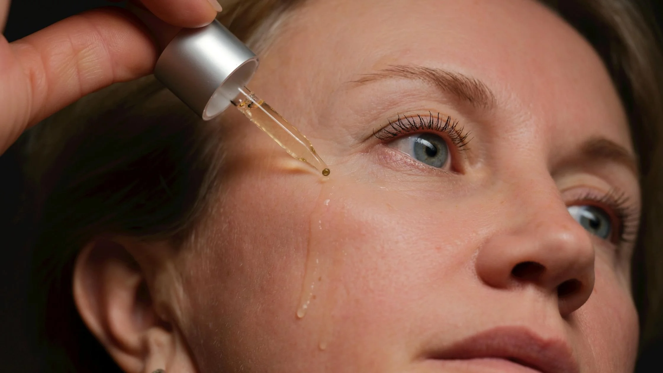 Close-up of a person applying facial serum with a dropper