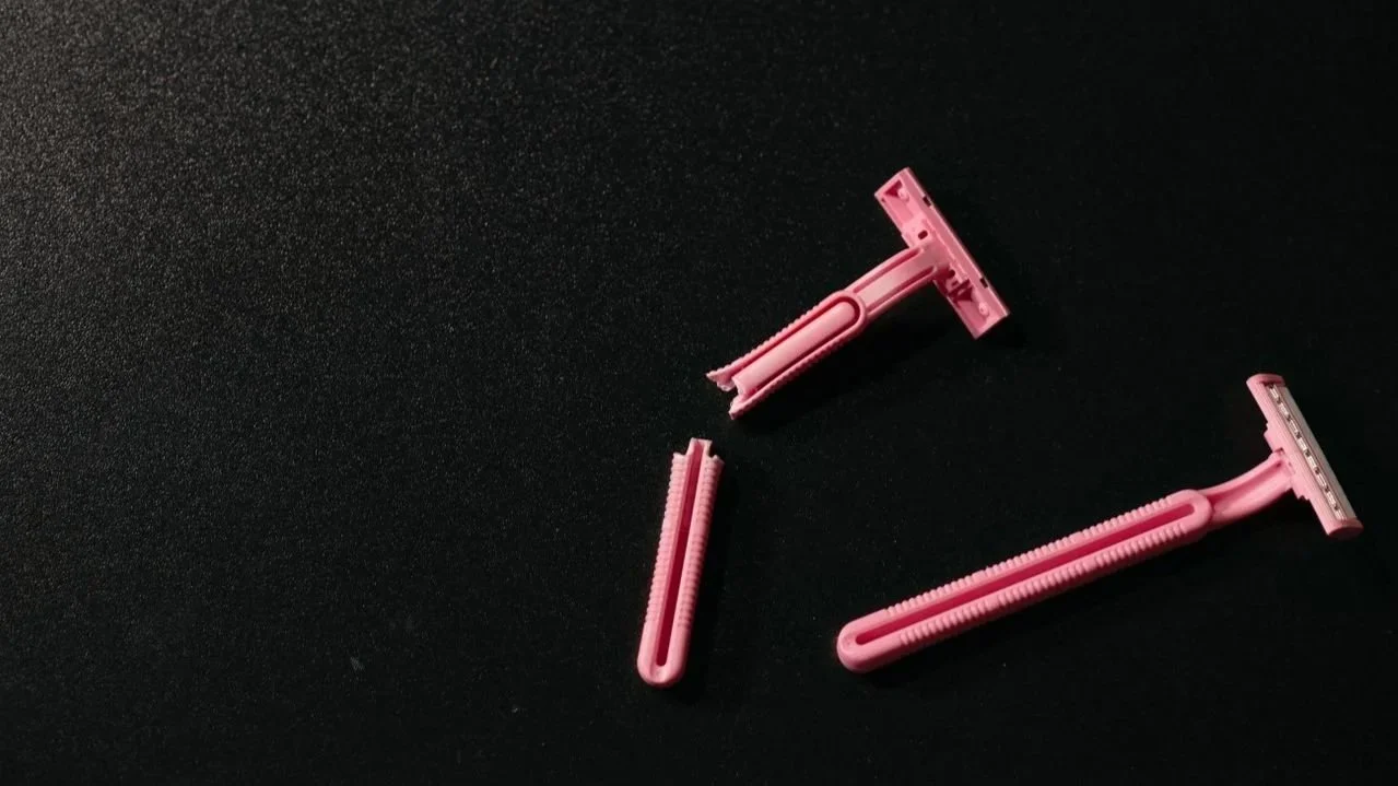 Broken pink disposable razors on a dark surface