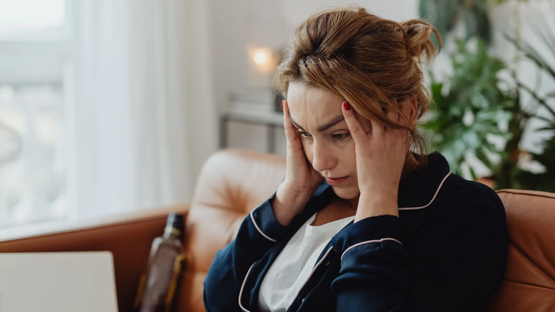 Woman sitting on a couch holding her head and looking stressed