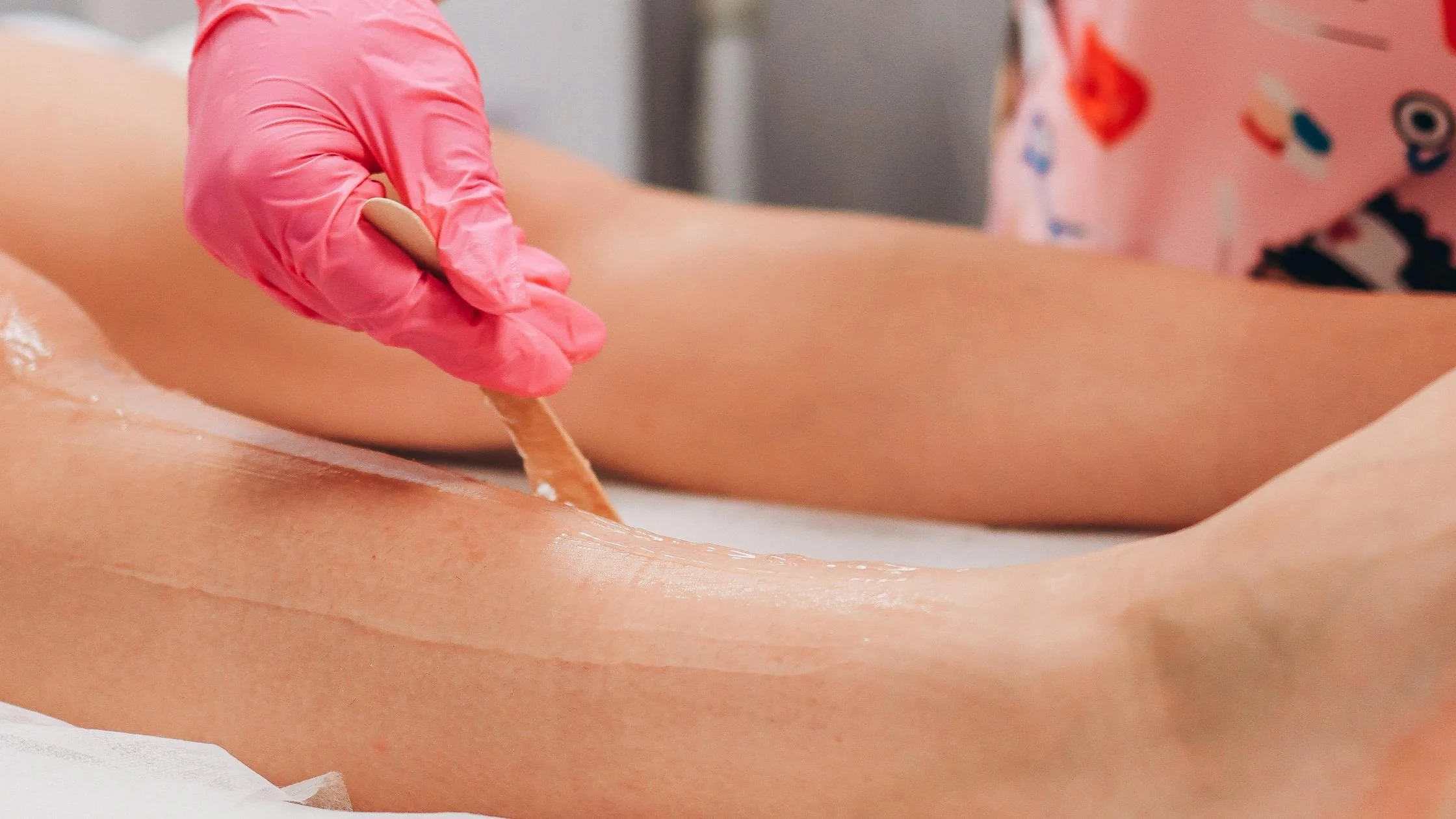 Close-up of leg waxing with a wooden spatula applying wax