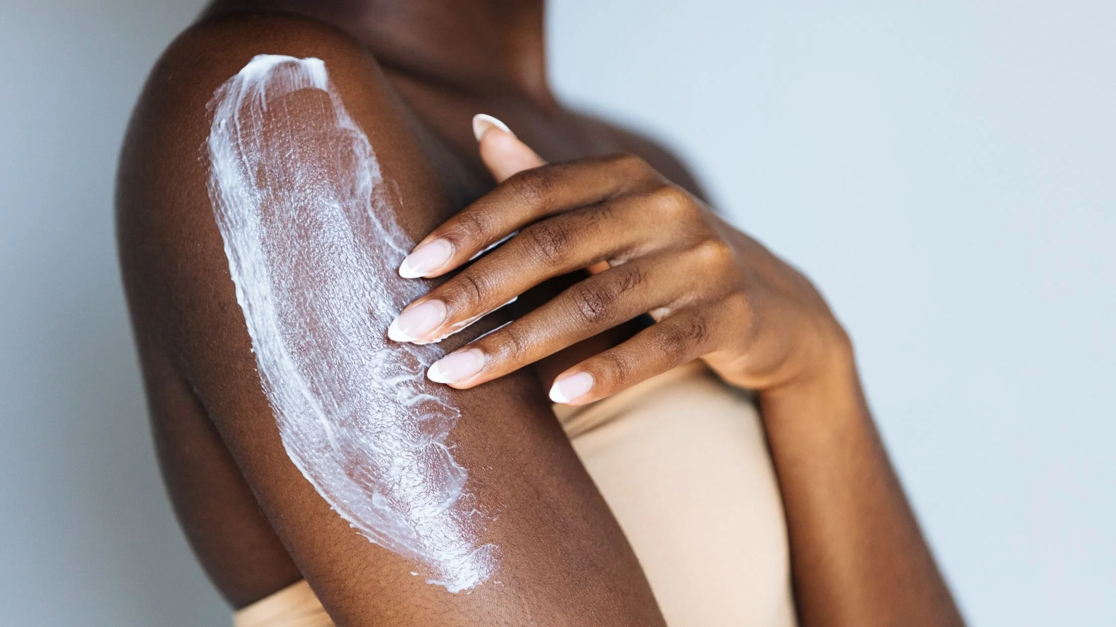 Person applying lotion to their upper arm