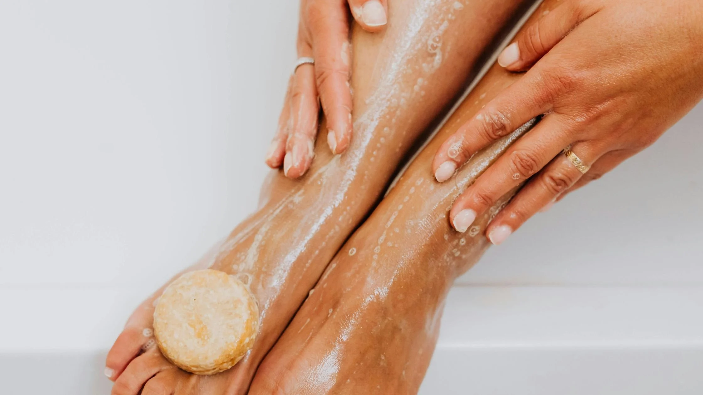 Person washing legs with soap in the shower