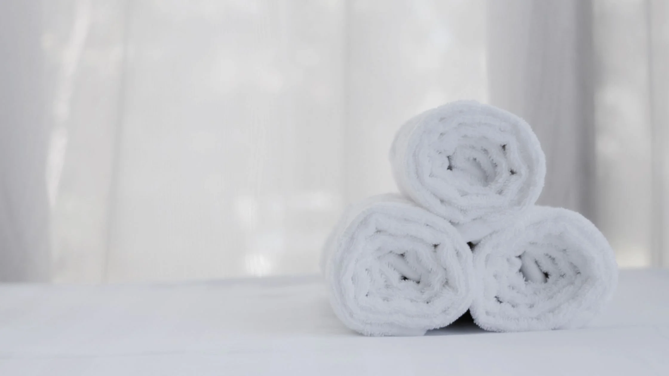 Stack of rolled white spa towels on a treatment table