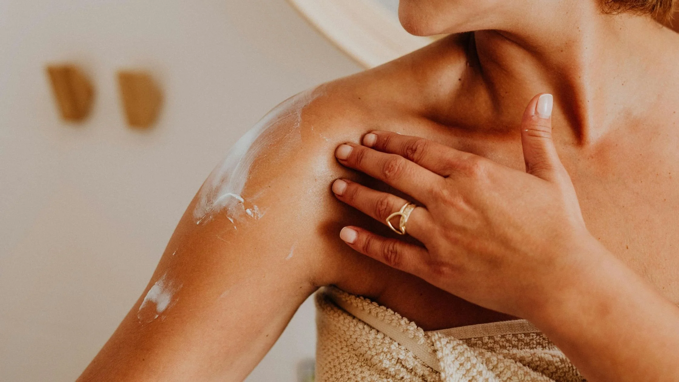 Person applying lotion to their shoulder and upper chest