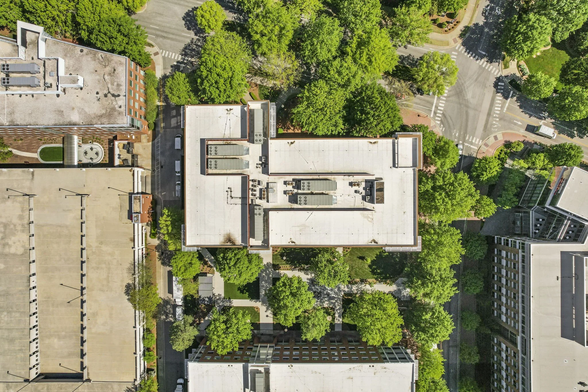 Aerial view of city buildings surrounded by green trees and streets.