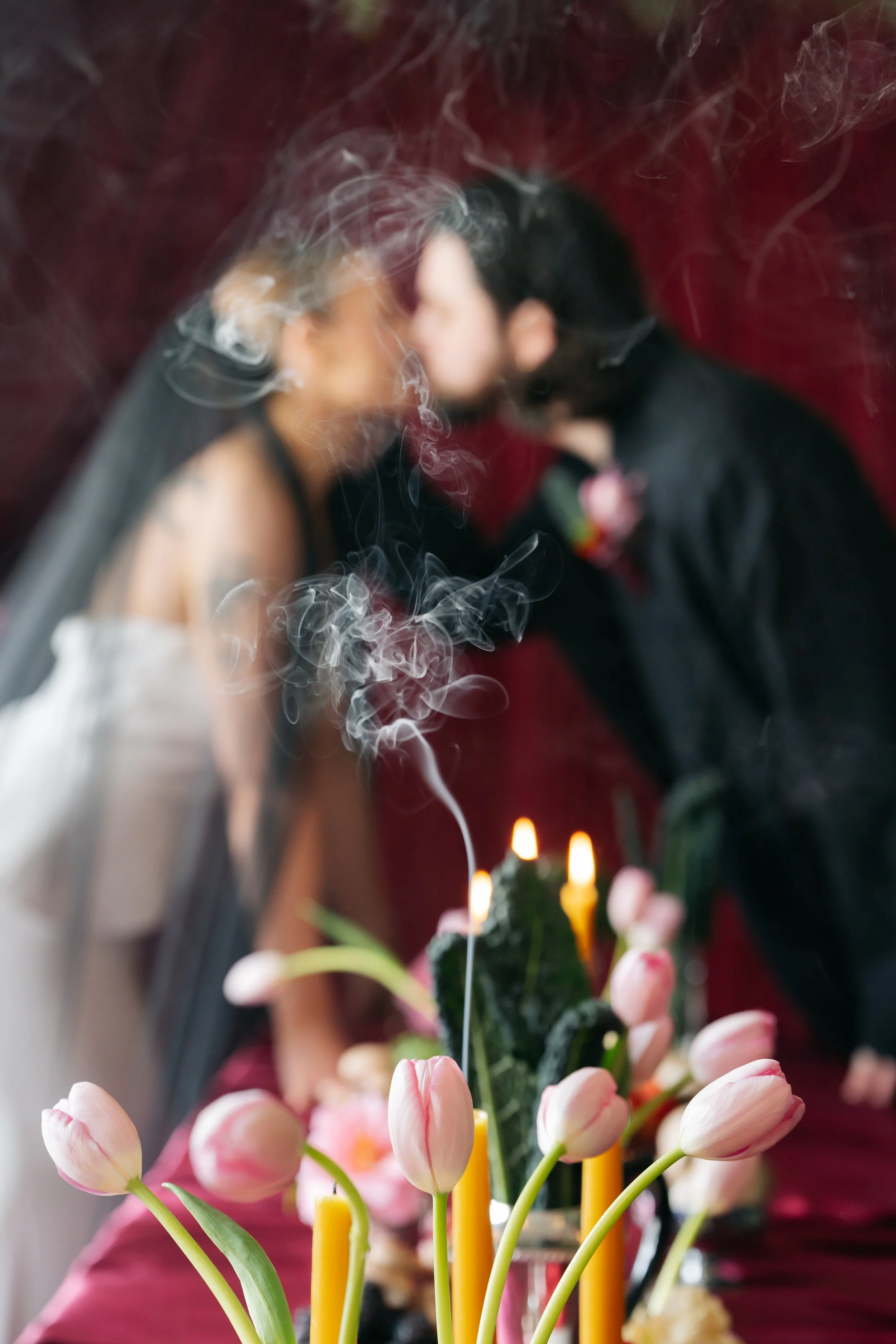 Bride and groom kissing. Red drapes and table drapes styled by alternative wedding stylist Cherry on Pop in Lanarkshire