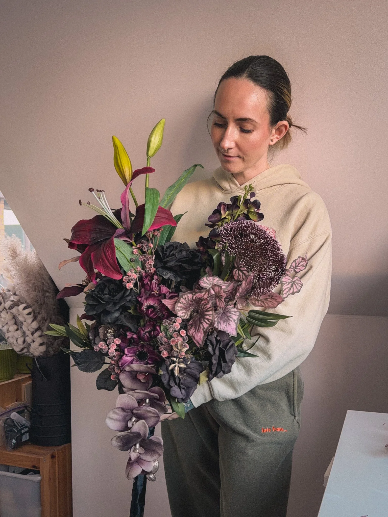 Woman holding a large bouquet of dark and pink flowers indoors.