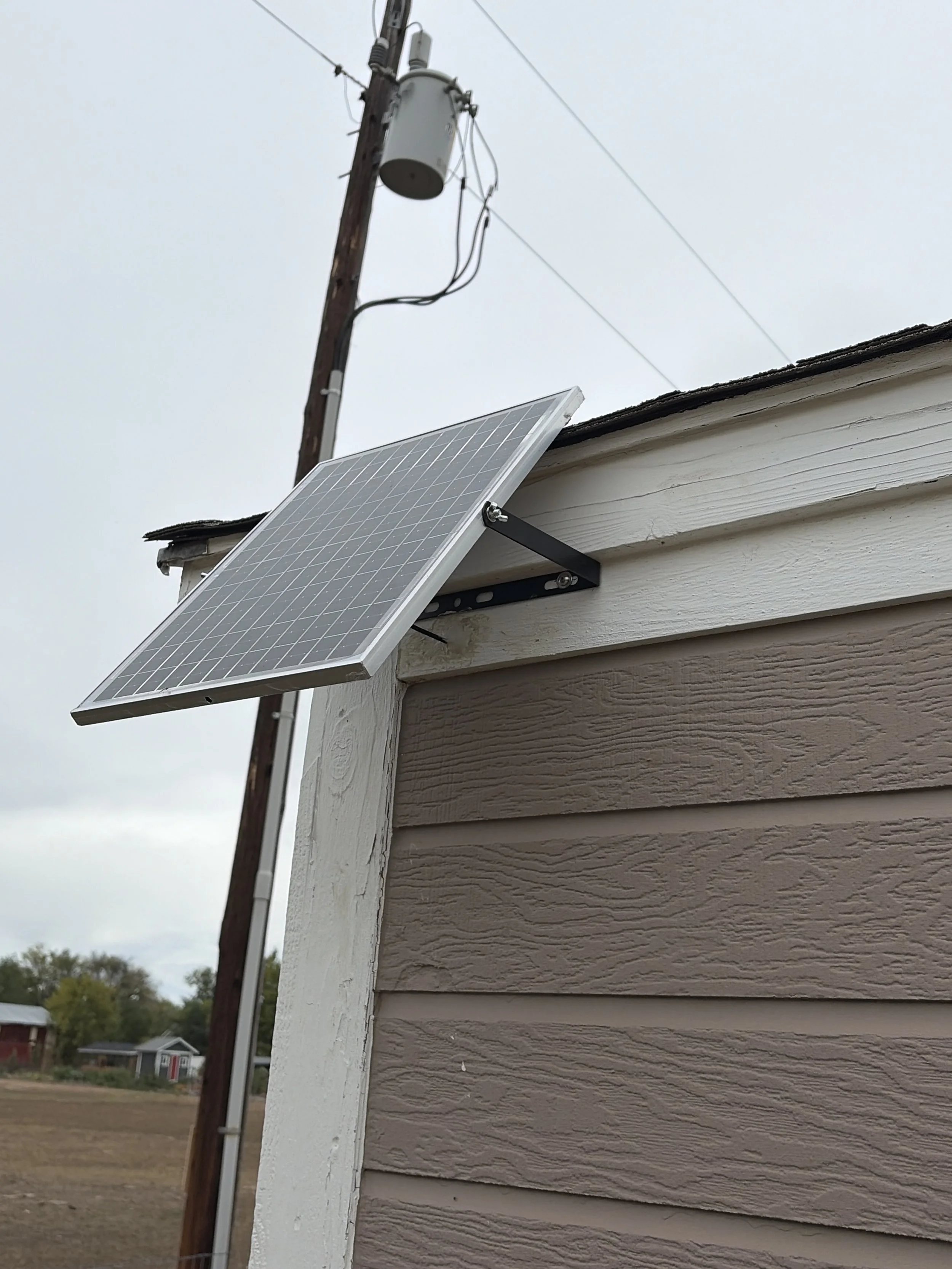 Solar panel on adjustable bracket mounted to shed fascia to power a solar exhaust fan in Boulder County, CO