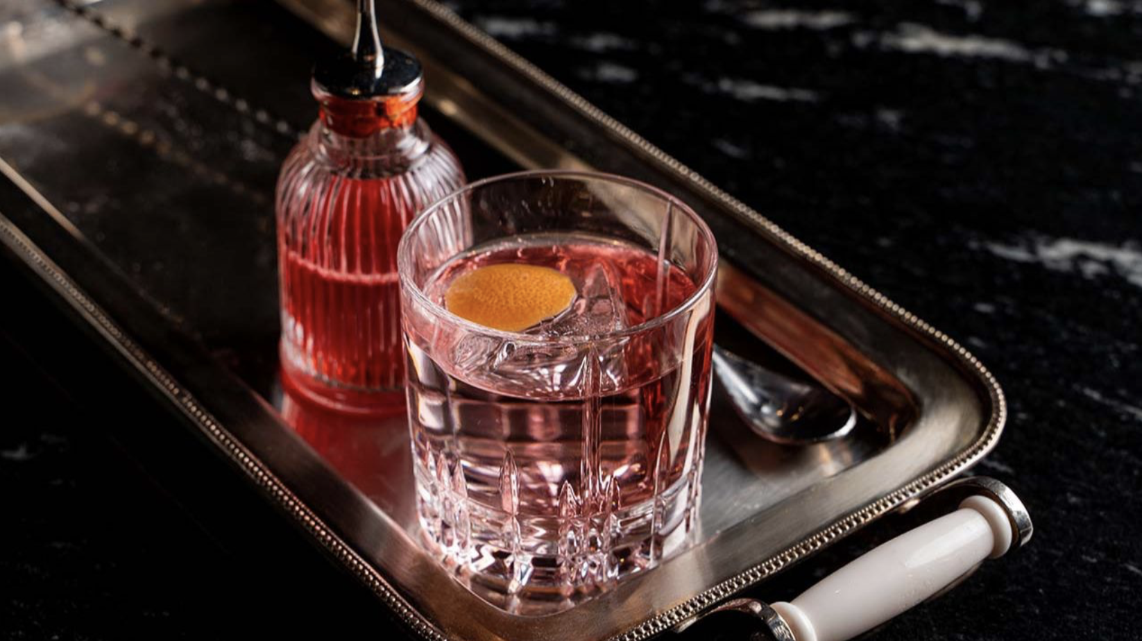 A red liquid in a bottle and a bar glass full of that red liquid