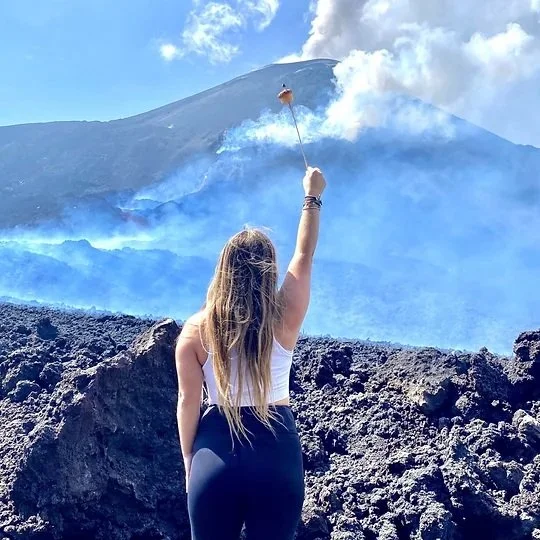 Guatemala, Woman with long hair waving a small flag at a volcanic eruption surrounded by smoke and ash.
