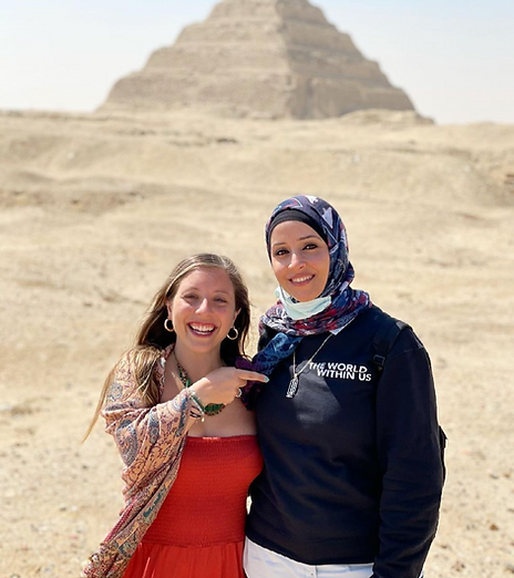 Two smiling women standing in front of the Pyramid of Kukulcán at Chichen Itza in Mexico, with one pointing at the other.