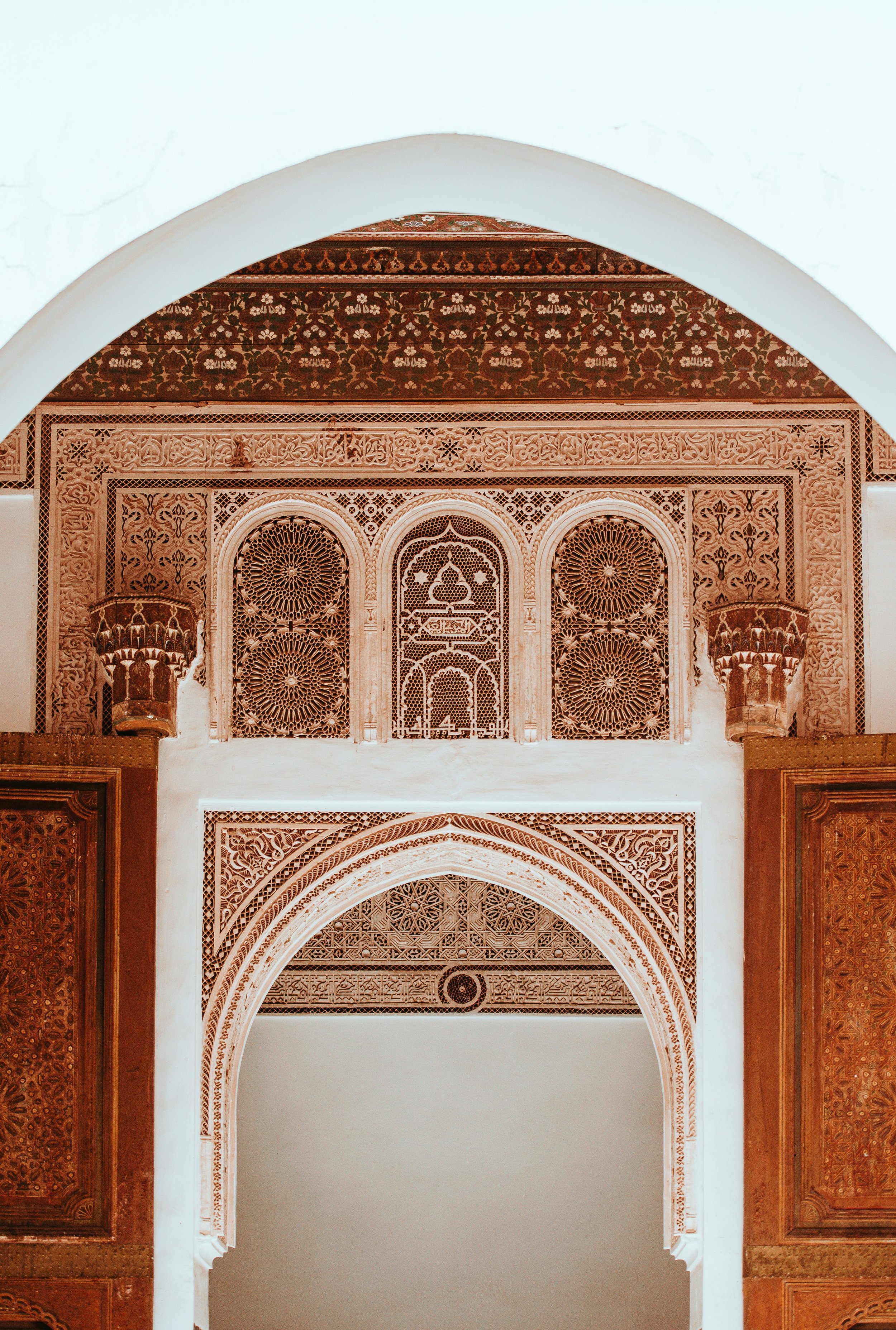 Close-up view of intricate Islamic architectural carvings on a wall, featuring geometric patterns, floral motifs, and arches.