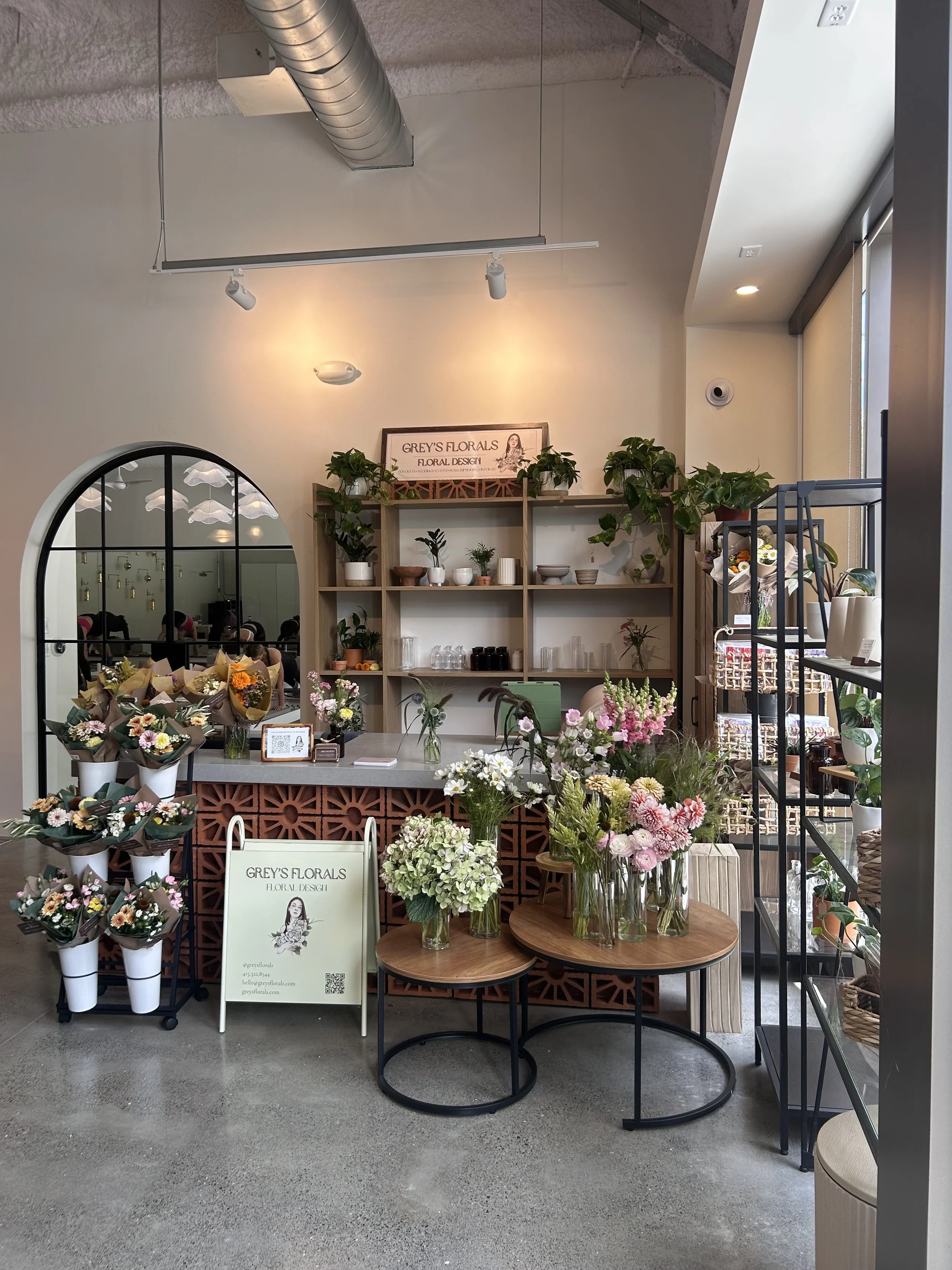 Flowers and floral arrangements displayed inside a flower shop with shelves of plants and decorative items.