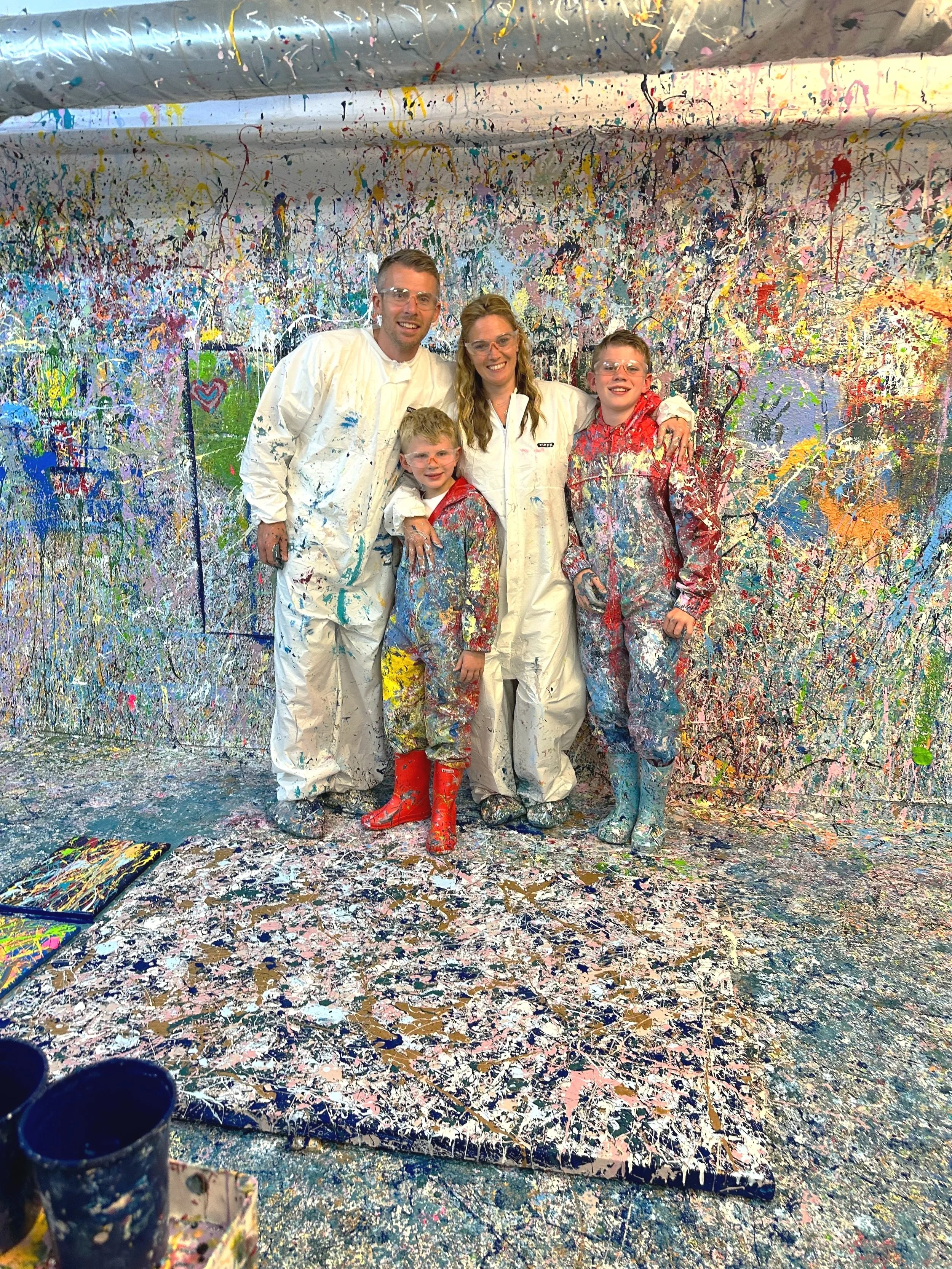 Family adding colourful paint to a 100 × 150 cm shared canvas