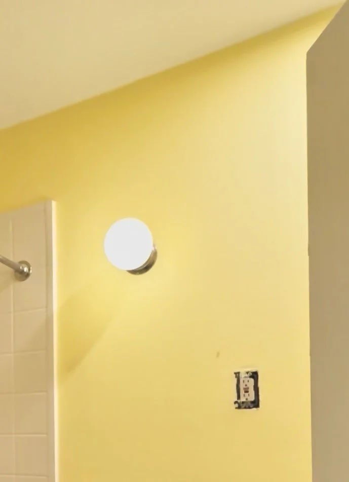 A "after" image of repaired wall using skim coating to prep the surface for painting yellow.