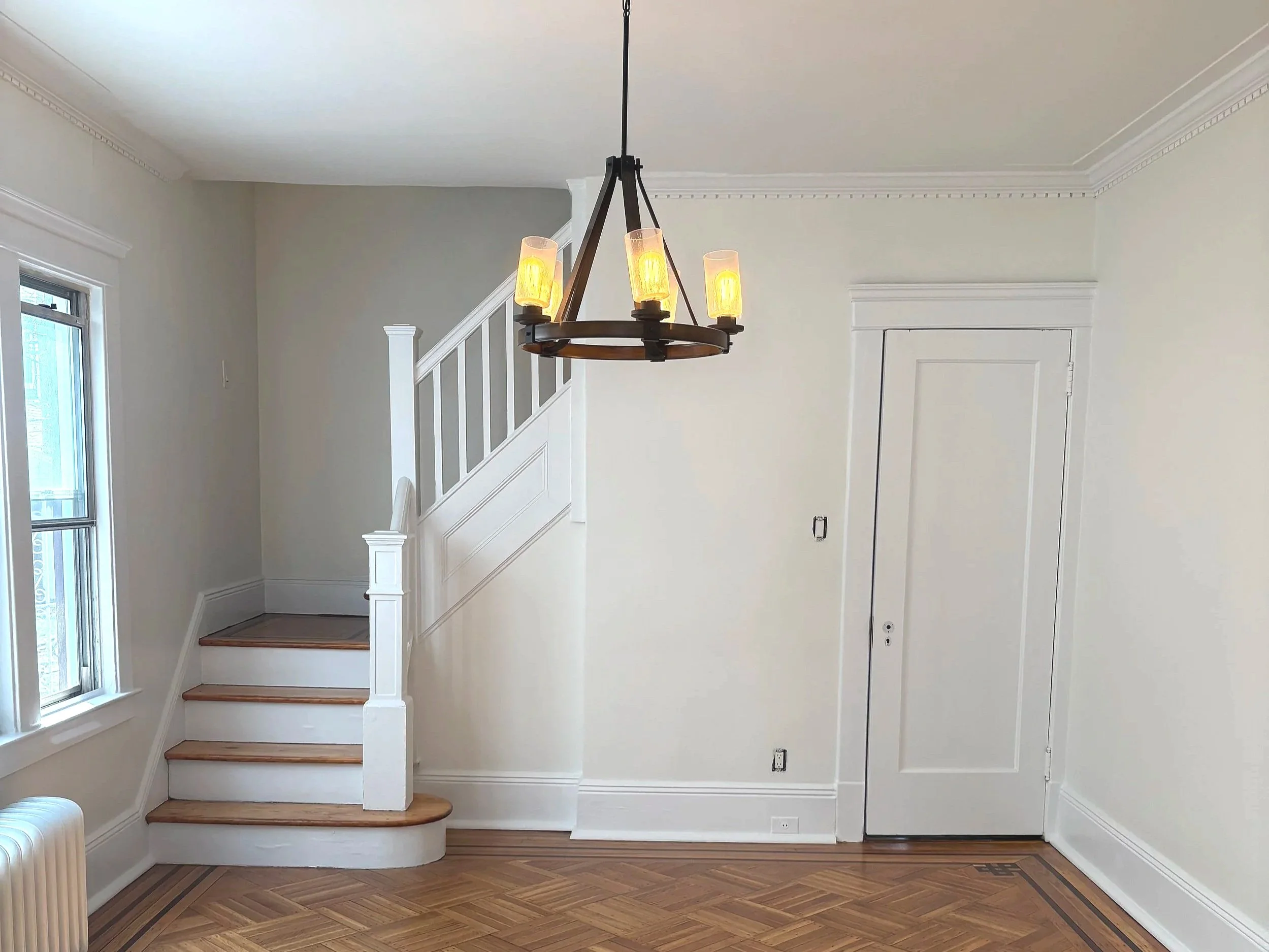 View of a recently repainted hallway featuring neutral walls, white molding, and newly finished hardwood flooring.