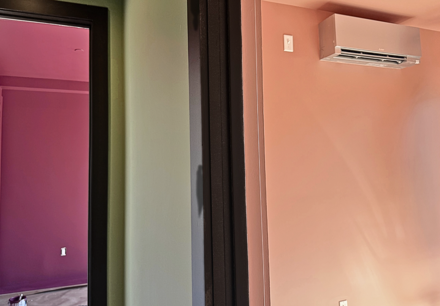 Photo of 3 walls painted in pink, light green, and peach with dark brown trim