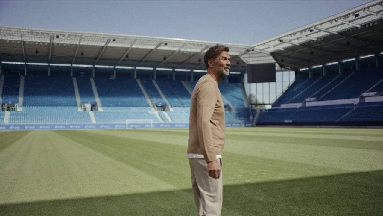 Man standing on the grass field inside an empty soccer stadium