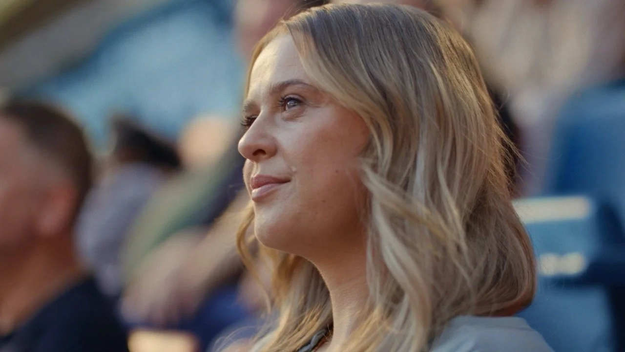 Close-up profile portrait of a blonde woman looking upward at an outdoor event.