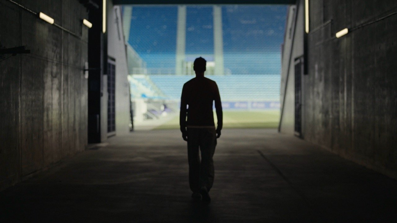 Silhouetted person walking through a stadium tunnel toward the field