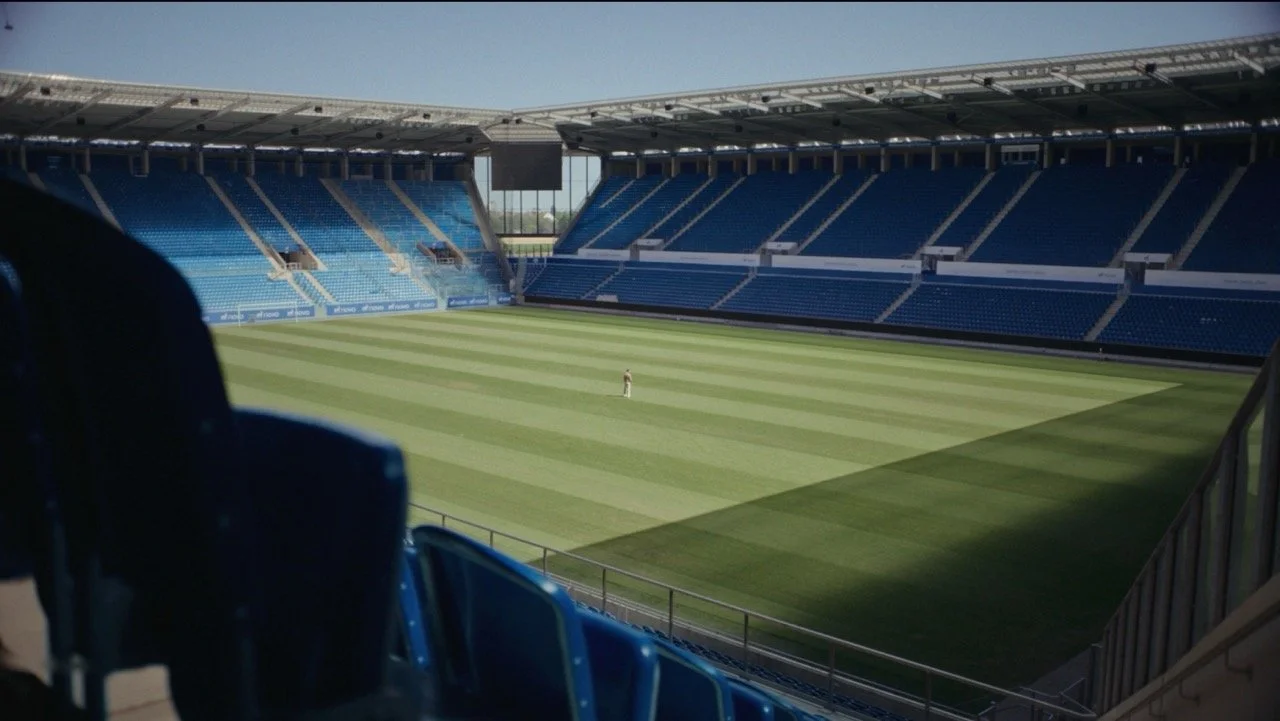 Empty soccer stadium with blue spectator seats and a freshly striped green field