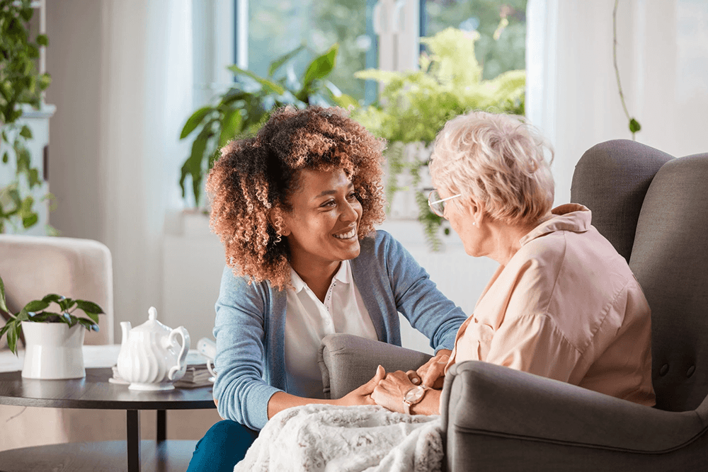 woman crouched next to an older woman in a chair