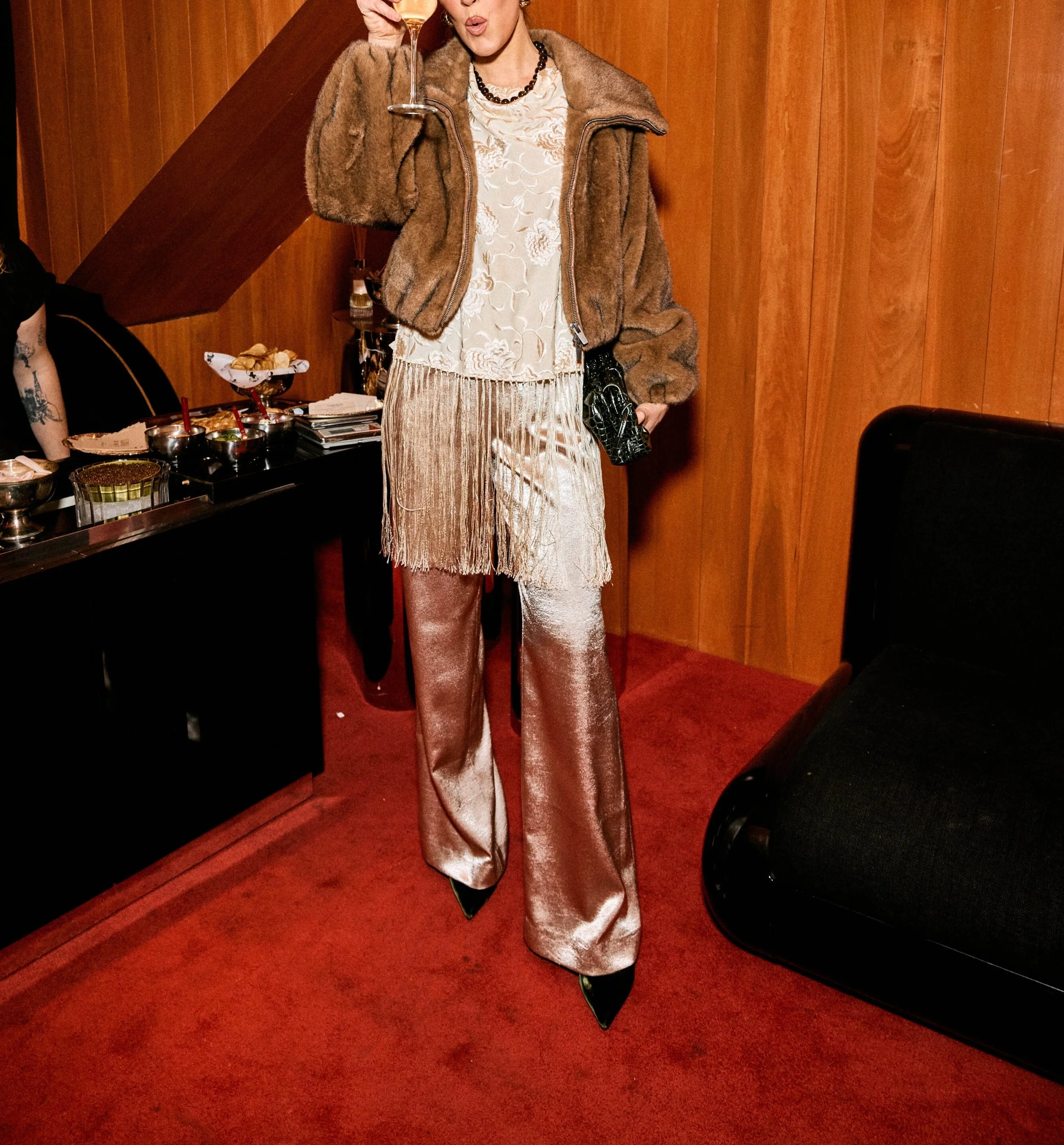 Woman in vintage-inspired outfit holding champagne inside Pearl Box, a stylish cocktail bar in Soho NYC