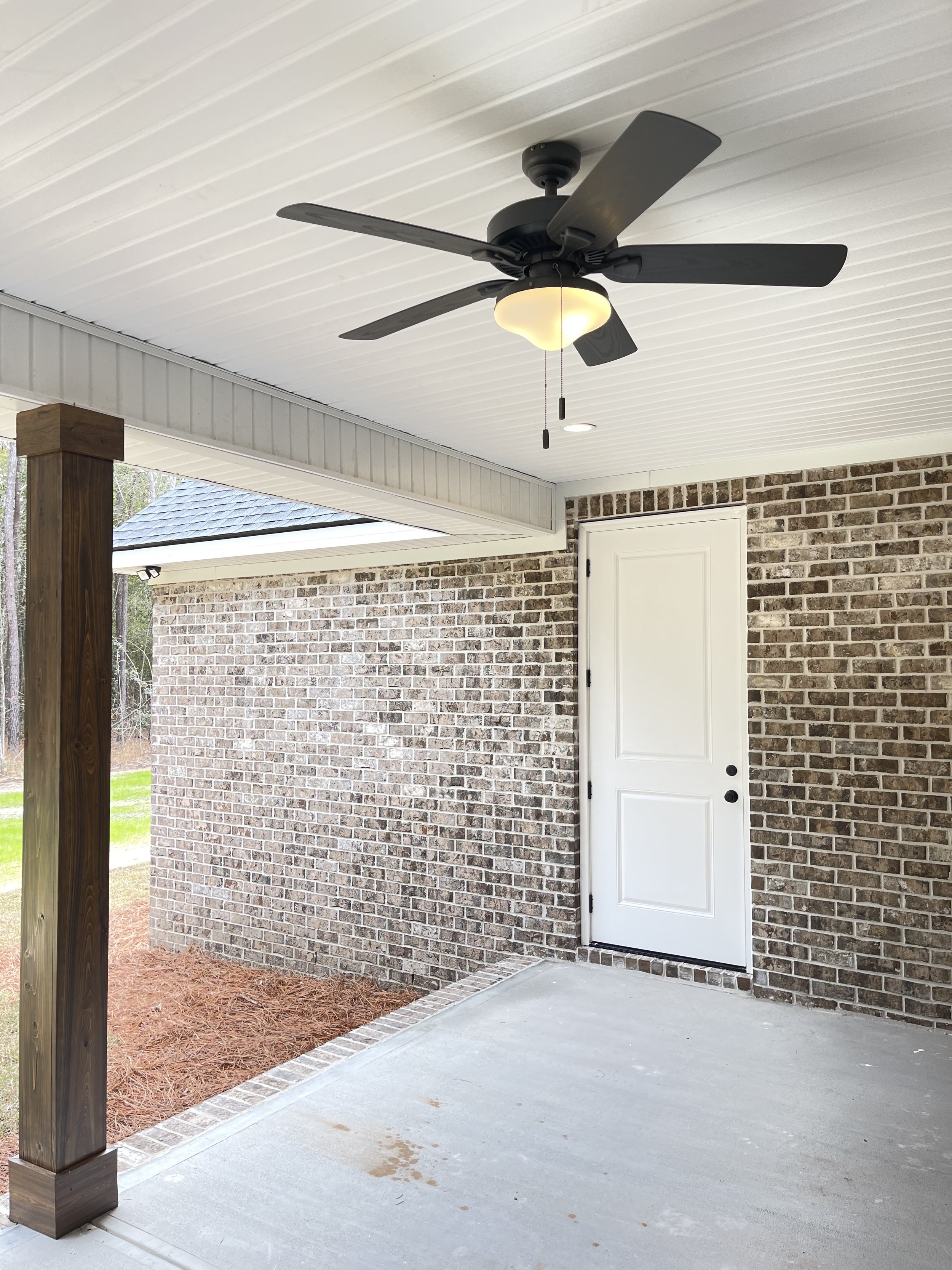 Back porch view of a custom home with brick and vinyl siding with wood stained columns.