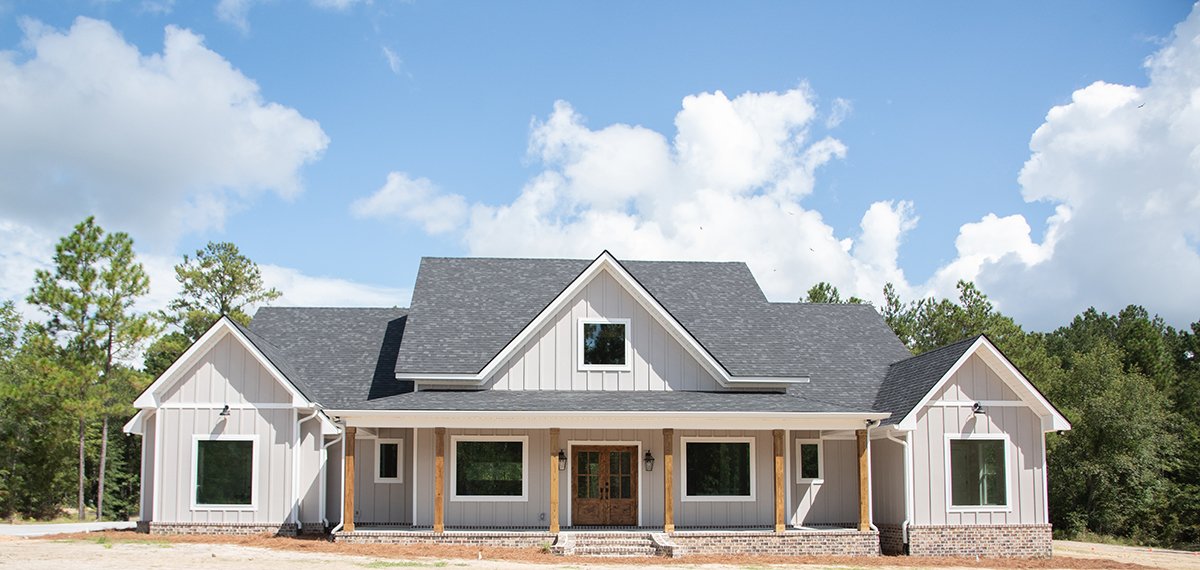 Custom modern grey with white trim farmhouse build with stained wood columns and front door.