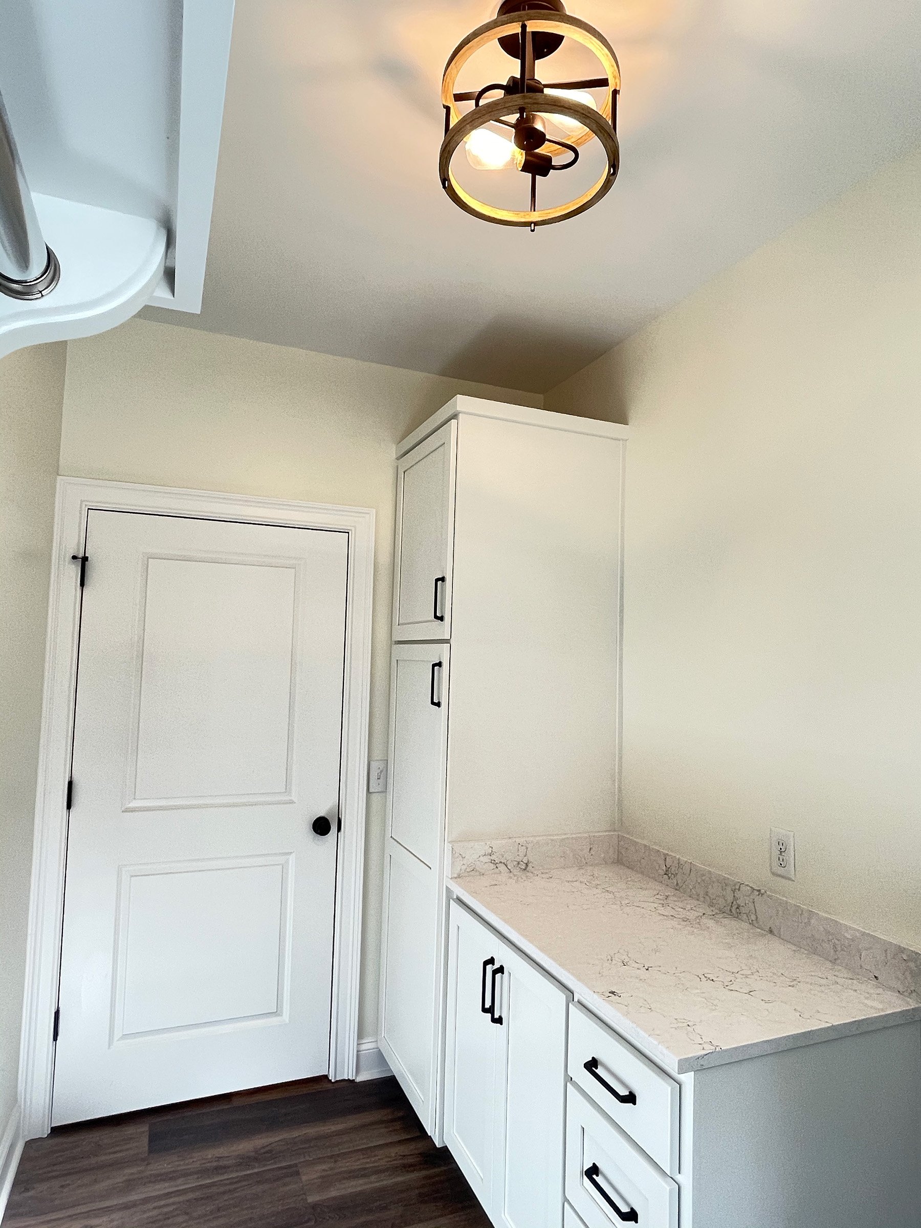 Custom built laundry room cabinets with black hardware.