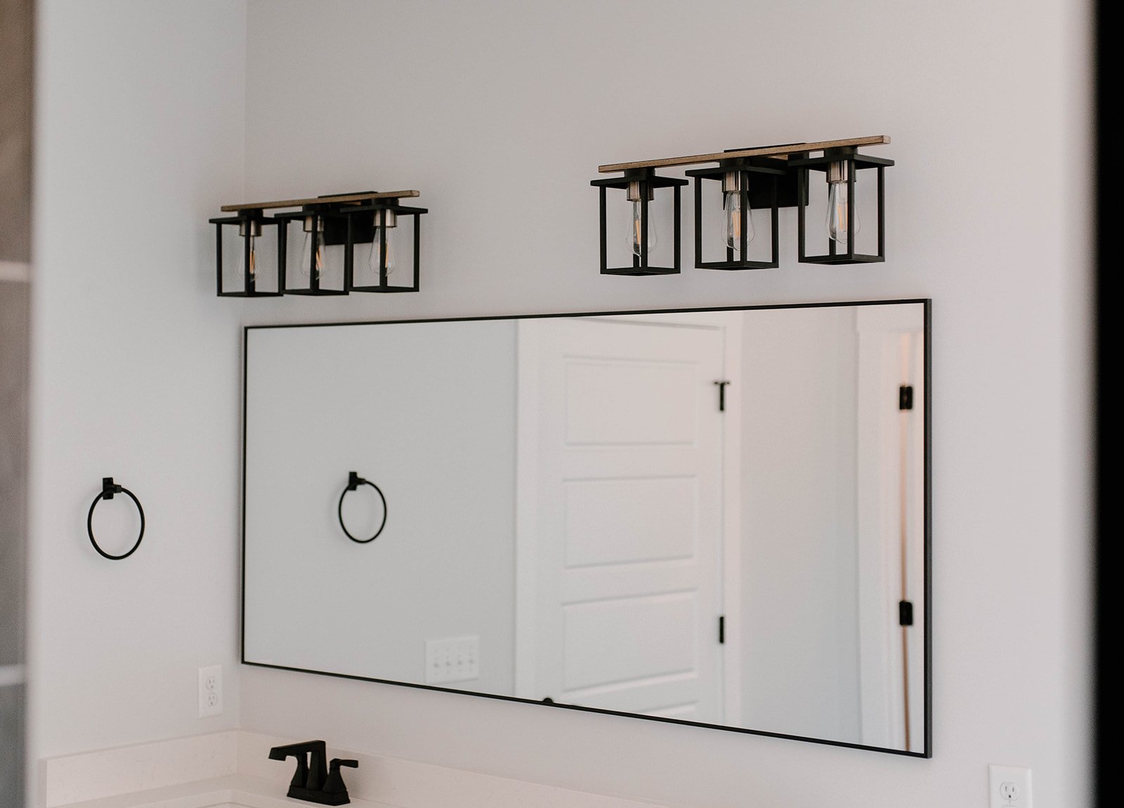 Master bathroom with matte black vanity lights, mirror, bath hardware and faucets.