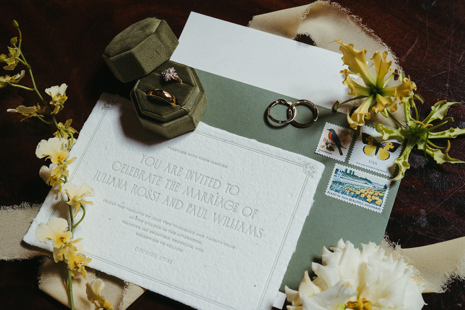 Flatlay of a letterpress wedding invitation with handmade paper and curated vintage stamps