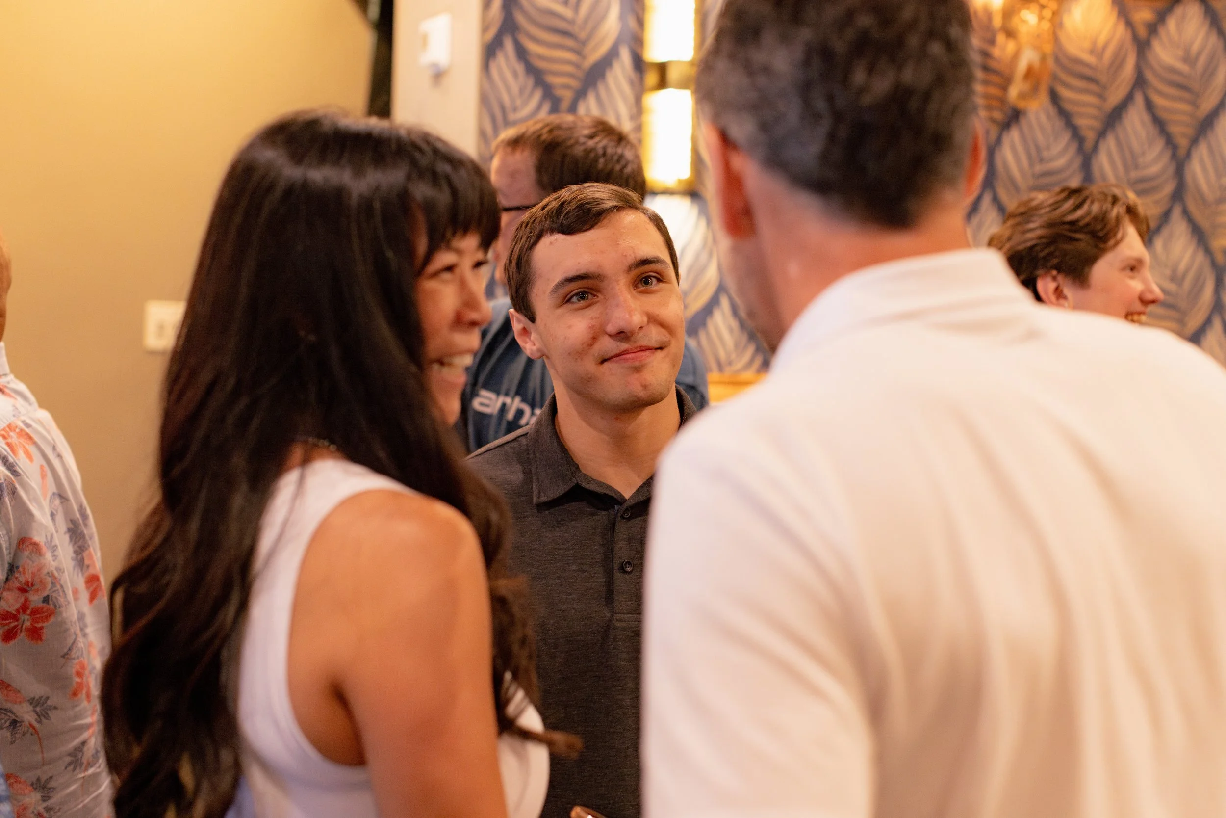 Group of people chatting and smiling at a social event or gathering indoors.