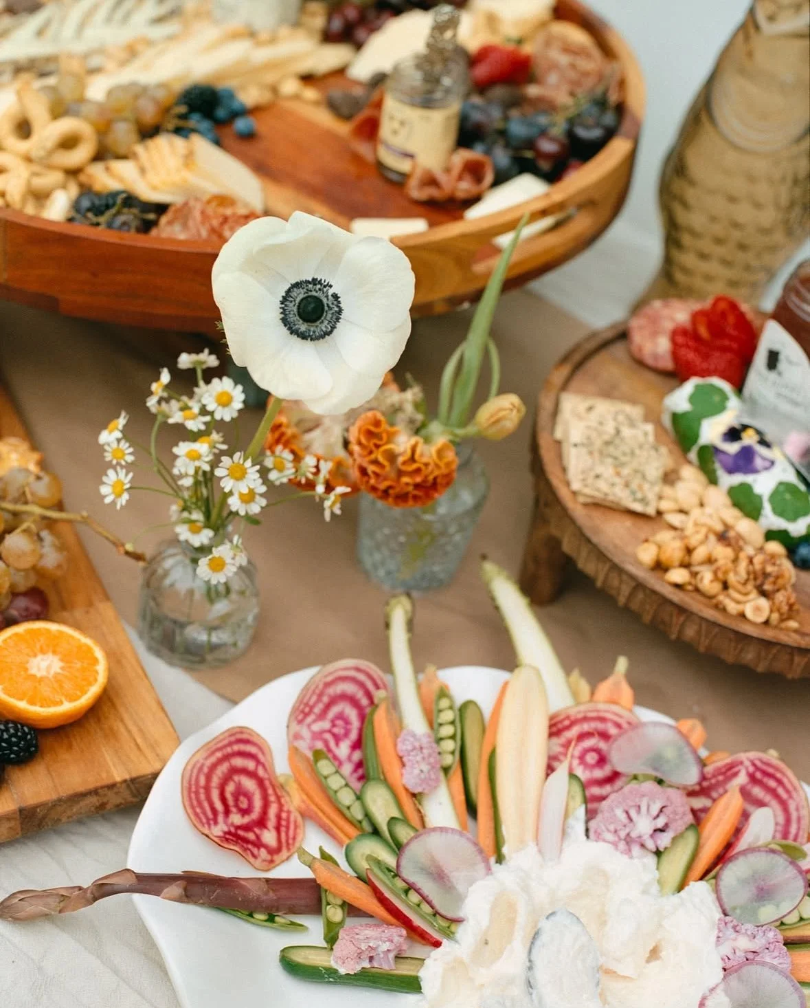 Vegetable and fruit platter with sliced radishes, carrots, cucumbers, and unidentifiable dairy or cheese at a festive gathering